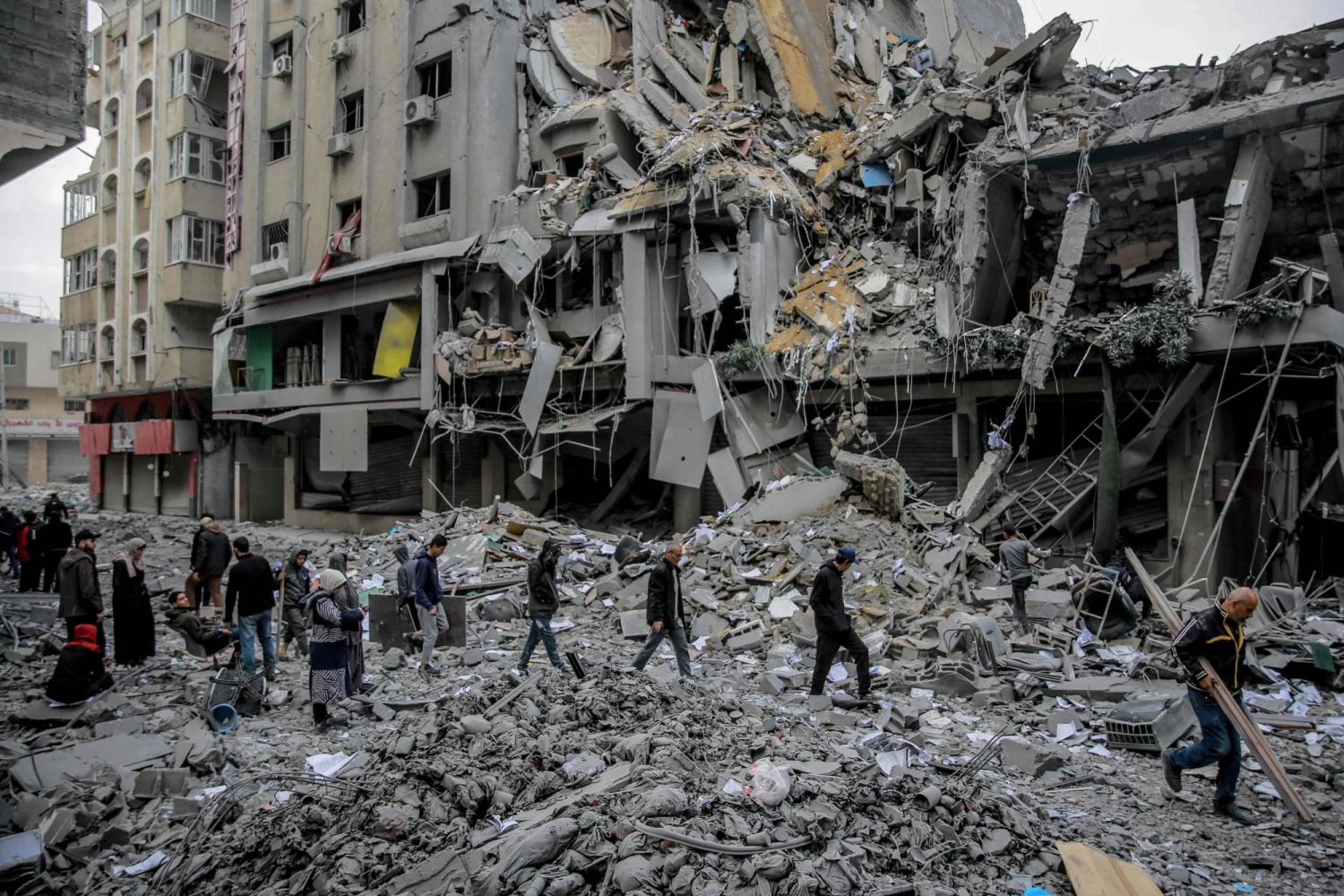 فلسطينيون يسيرون وسط أنقاض المنازل التي دمرها القصف الإسرائيلي في مدينة غزة (أ.ف.ب)