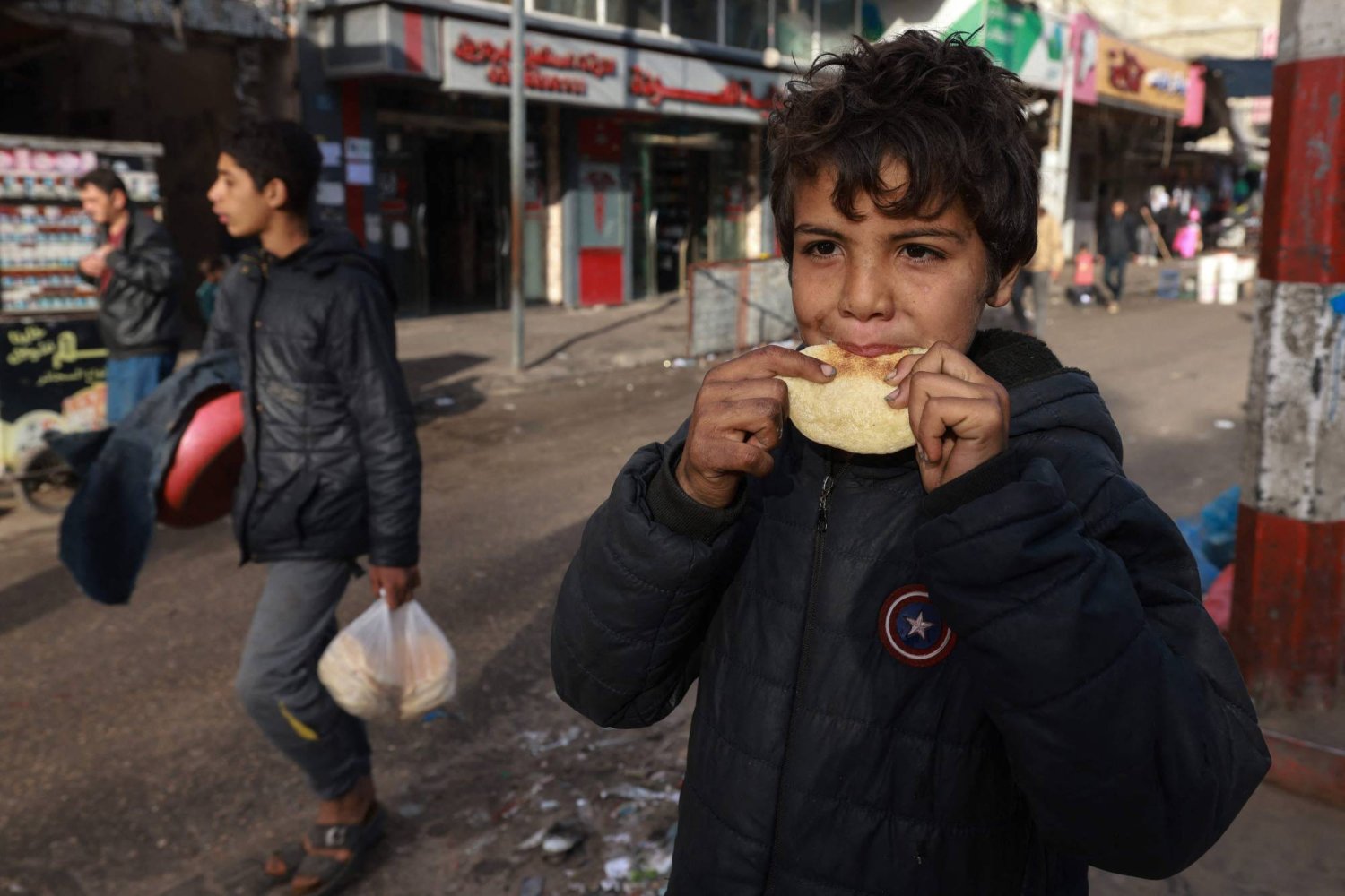 طفل فلسطيني يأكل خبزا في مخيم رفح جنوب قطاع غزة أمس (أ.ف.ب)