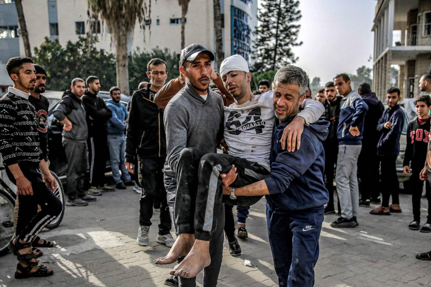رجلان يحملان مصاباً خارج المستشفى الأهلي العربي في مدينة غزة في 27 مارس (أ.ف.ب)