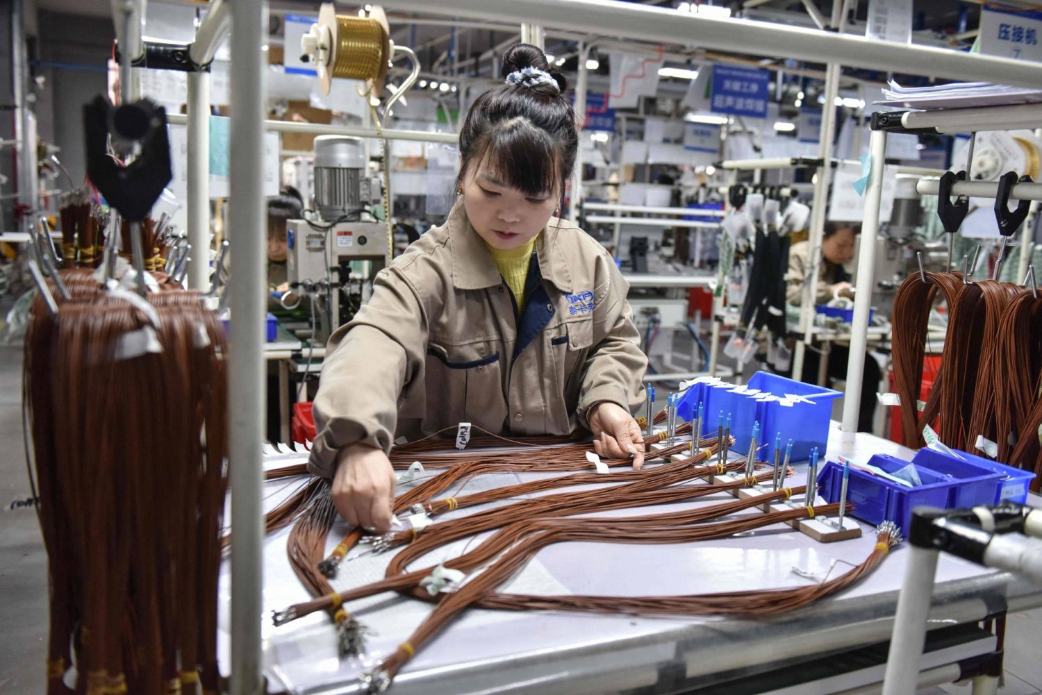 عاملة في أحد خطوط إنتاج الكابلات الكهربائية للسيارات بشرق الصين (أ.ف.ب)
