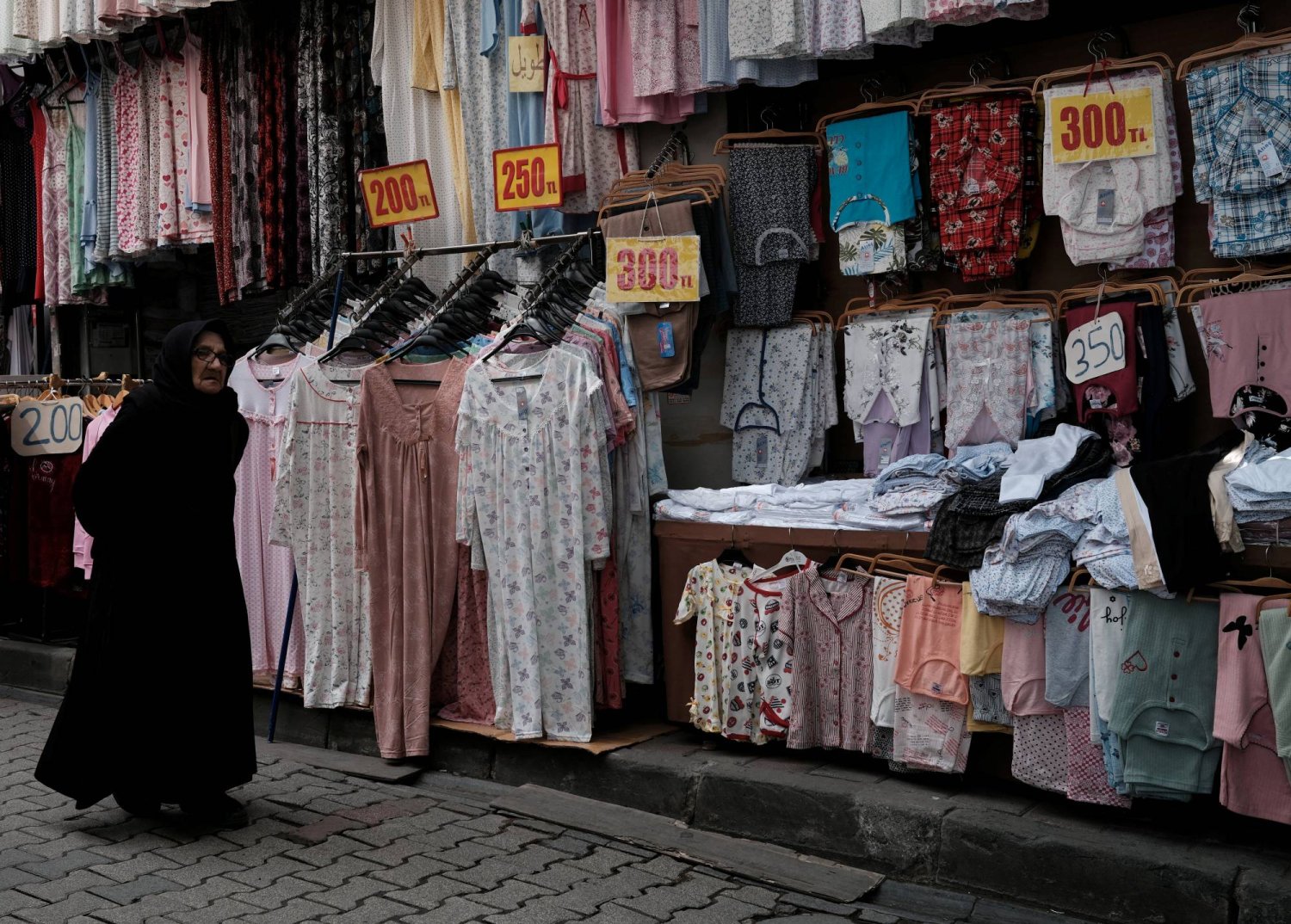 امرأة تمشي أمام متجر لبيع الملابس في منطقة تسوق شهيرة للطبقة المتوسطة بإسطنبول (رويترز)