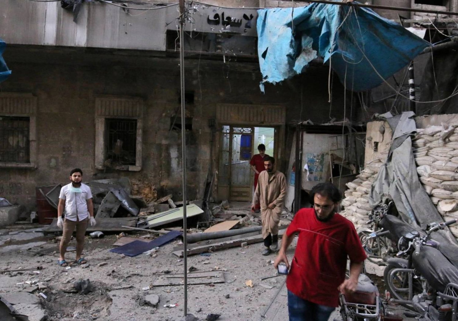 مسعفون يتفقدون الأضرار خارج مستشفى ميداني بعد غارة جوية على حلب في سوريا عام 2016 (رويترز)