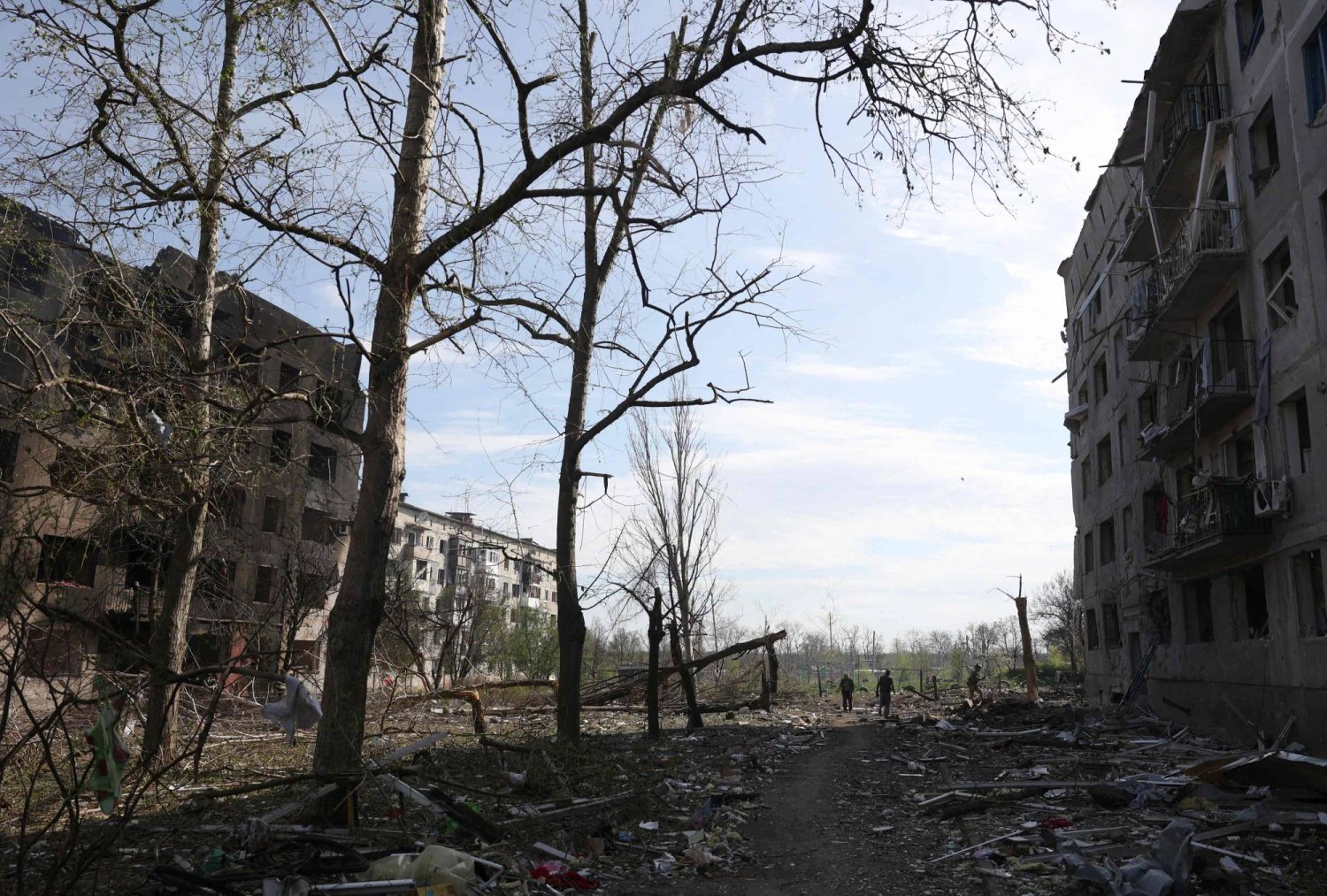 أوكرانيون يقفون بين المنازل التي دمرتها نيران المدفعية والغارات الجوية في قرية أوكريتين غير البعيدة عن بلدة أفدييفكا في منطقة دونيتسك (أ.ف.ب)