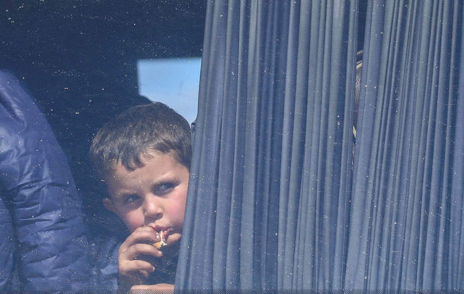 طفل ينظر من شباك حافلة لاجئين أرمن في طريقها إلى أرمينيا (أرشيفية - رويترز)