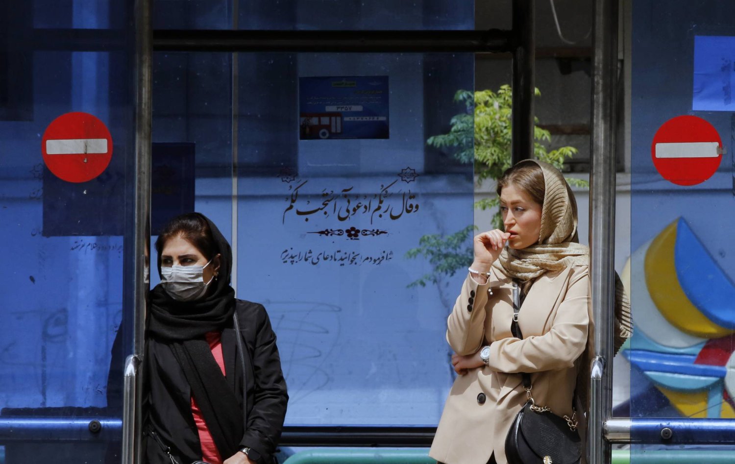 إيرانيات ينتظرن في محطة حافلات في طهران (إ.ب.أ)