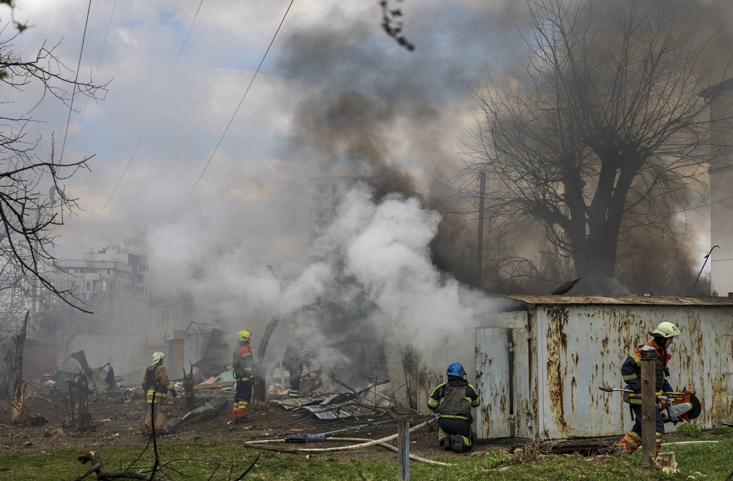 رجال إنقاذ أوكرانيون بمنطقة سكنية تعرضت لهجوم صاروخي في خاركيف (إ.ب.أ)