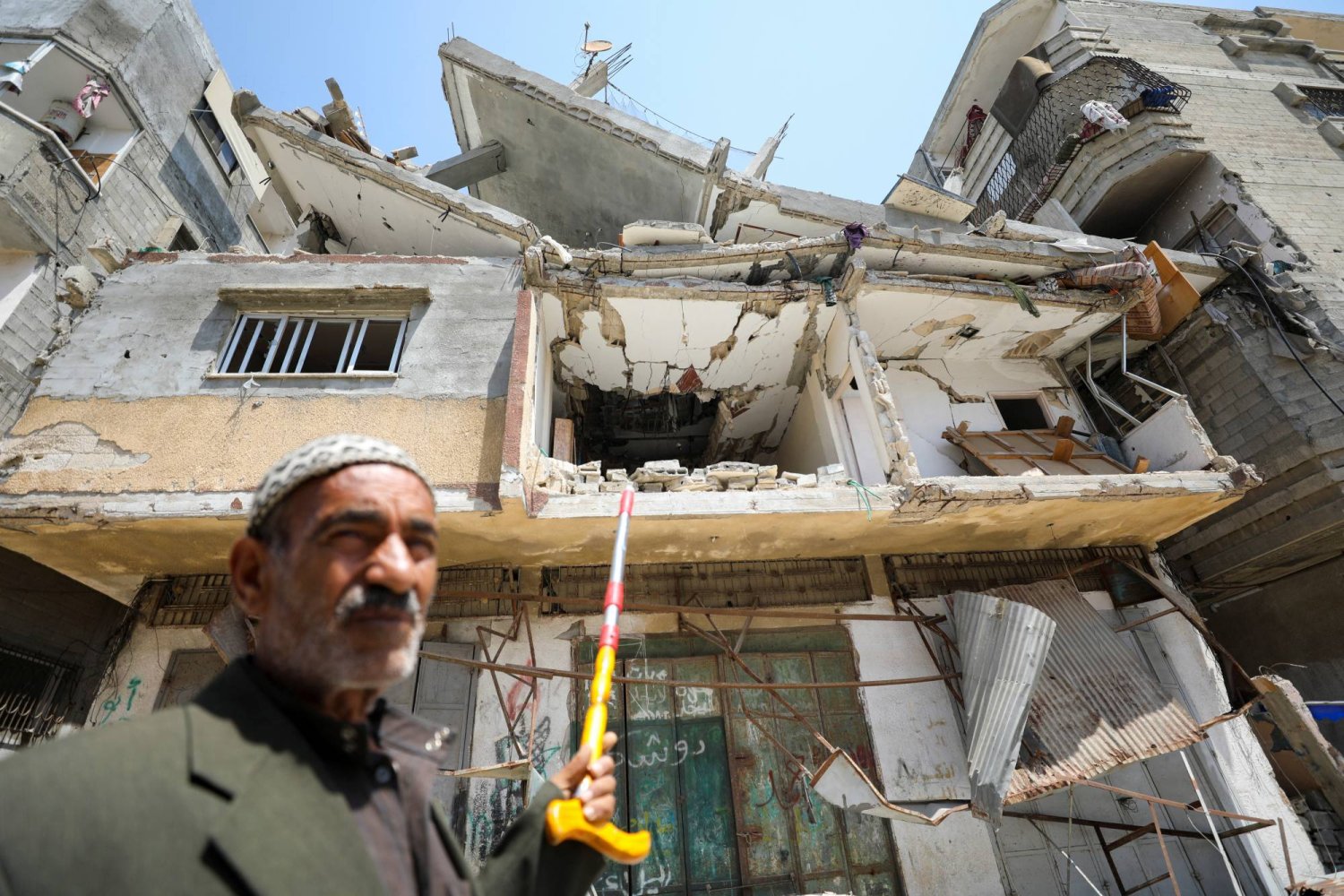 علي عروق الذي قضى حفيده زين بعد إصابته بمساعدات ألقيت جوا على غزة يشير إلى منزلهم الذي أصيب في غارة إسرائيلية الثلاثاء (رويترز)