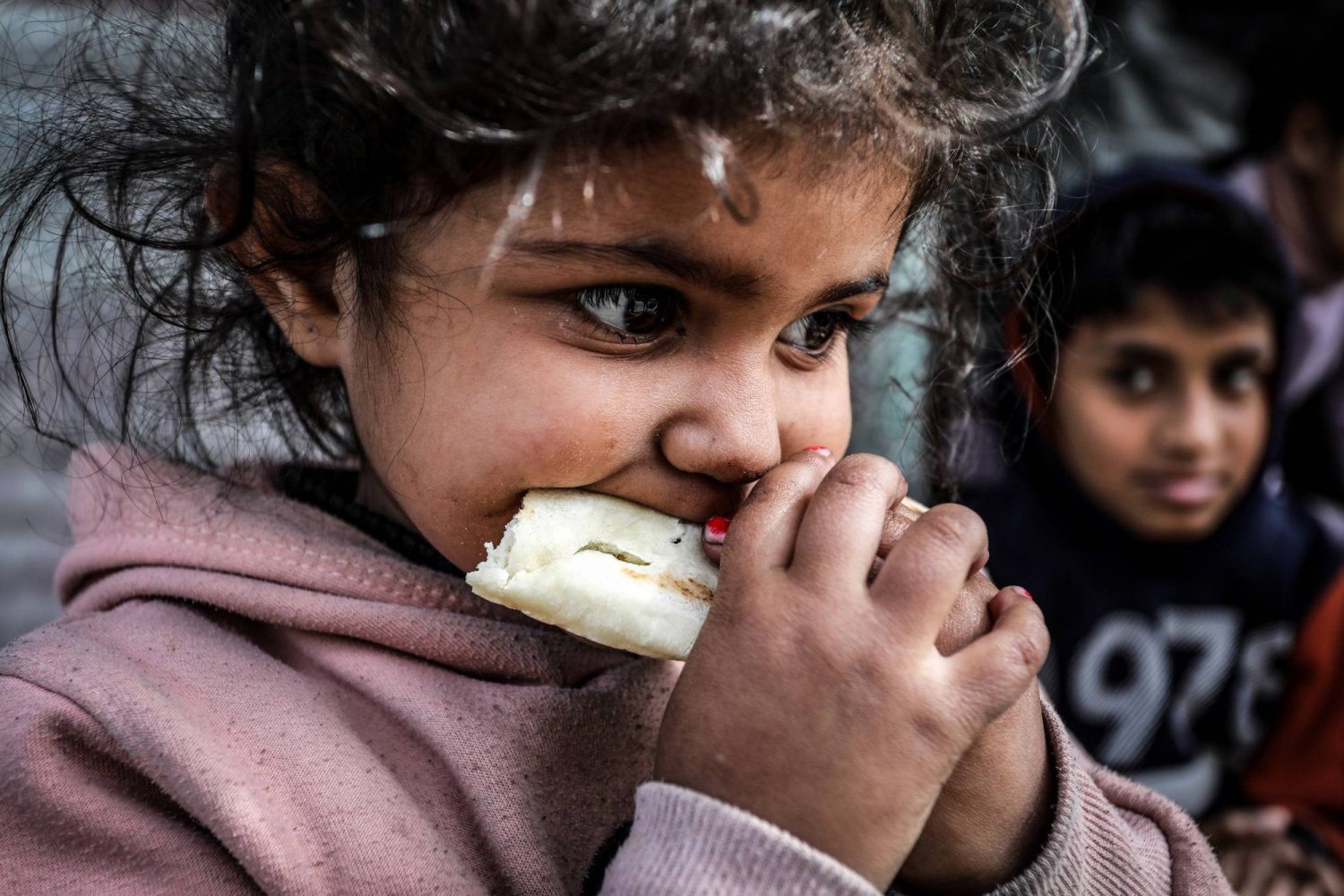فتاة فلسطينية نازحة تأكل كسرة خبز في مخيم برفح جنوب قطاع غزة (د.ب.أ)