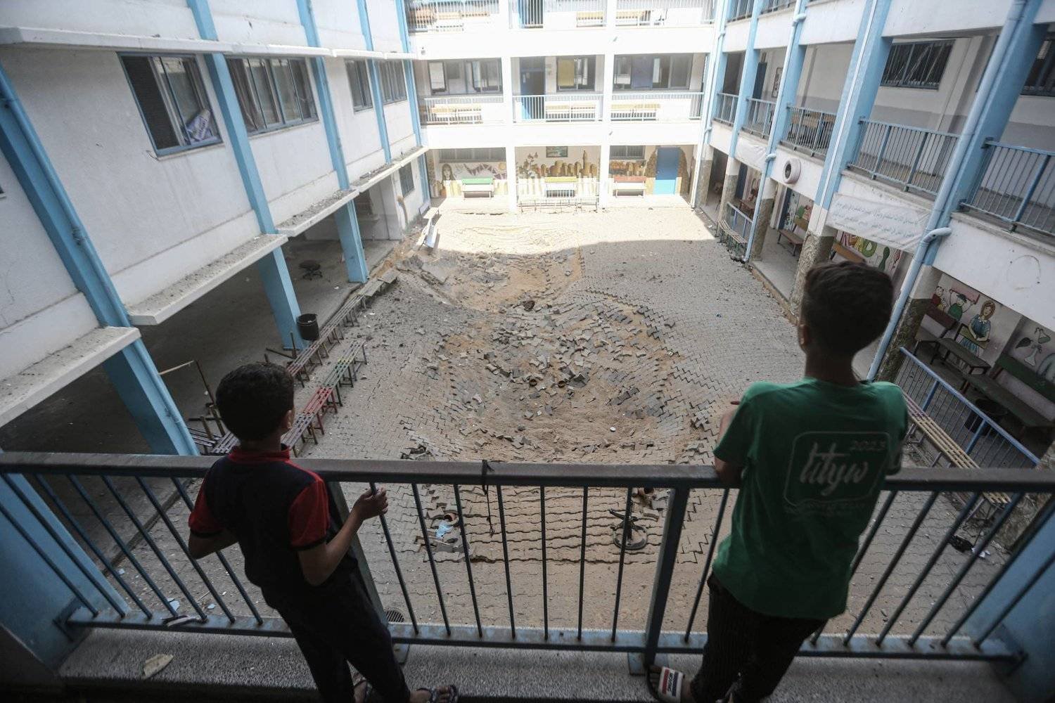 طفلان فلسطينيان يتفقدان الأضرار التي لحقت مدرسة تابعة للأونروا في أعقاب غارة جوية إسرائيلية (د.ب.أ)