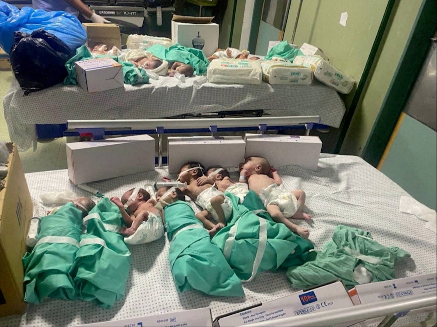 يتم وضع الأطفال حديثي الولادة في السرير بعد إخراجهم من الحاضنات في مستشفى الشفاء بغزة (رويترز)