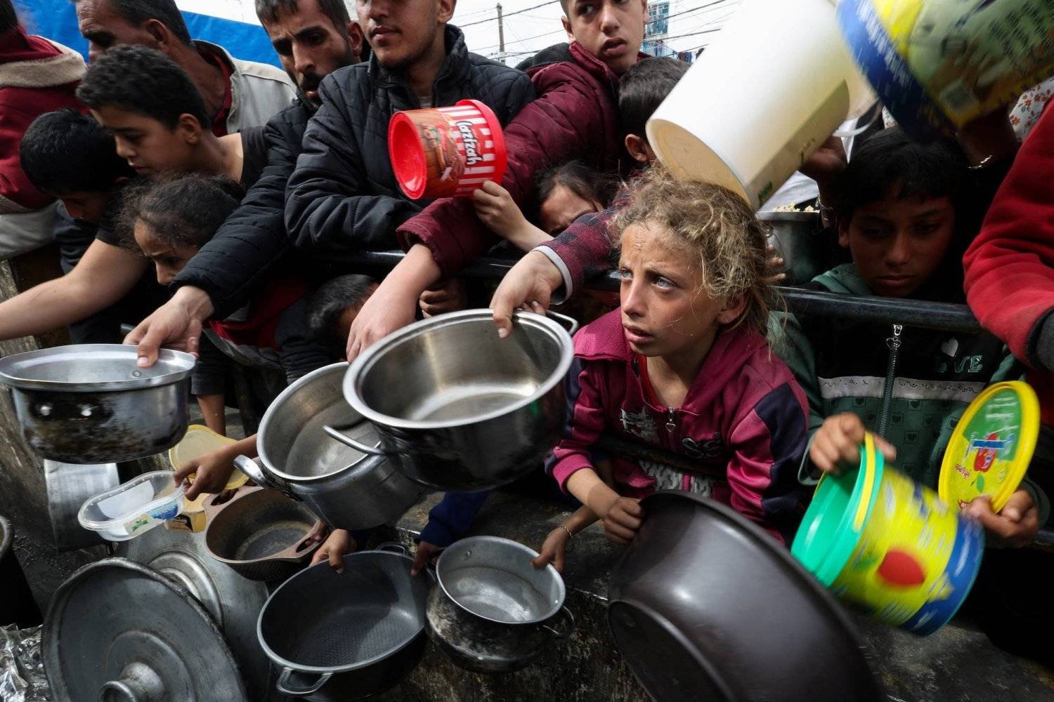 أطفال فلسطينيون ينتظرون المساعدات للحصول على الطعام (رويترز)