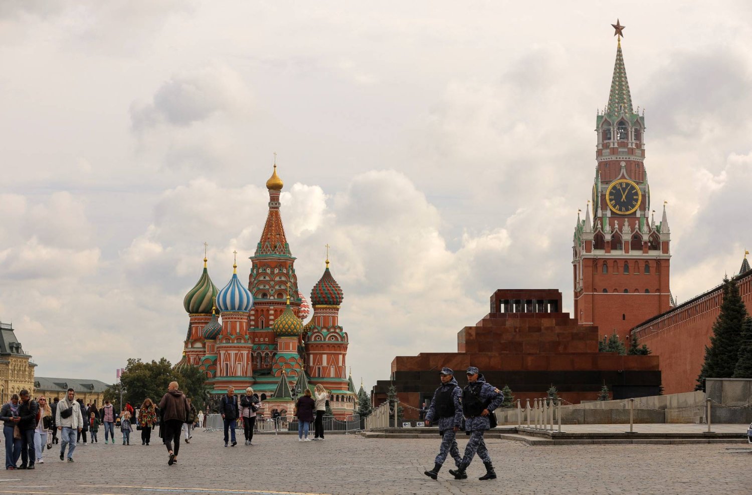 أشخاص يسيرون عبر الساحة الحمراء بالقرب من كاتدرائية القديس باسيل وبرج سباسكايا بالكرملين في وسط موسكو (رويترز)
