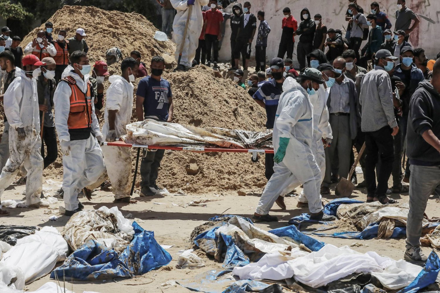 عاملون بالقطاع المدني الفلسطيني يحملون جثامين استُخرجت من مقابر جماعية يوم الأحد في «مجمع ناصر الطبي» بغزة (د.ب.أ)
