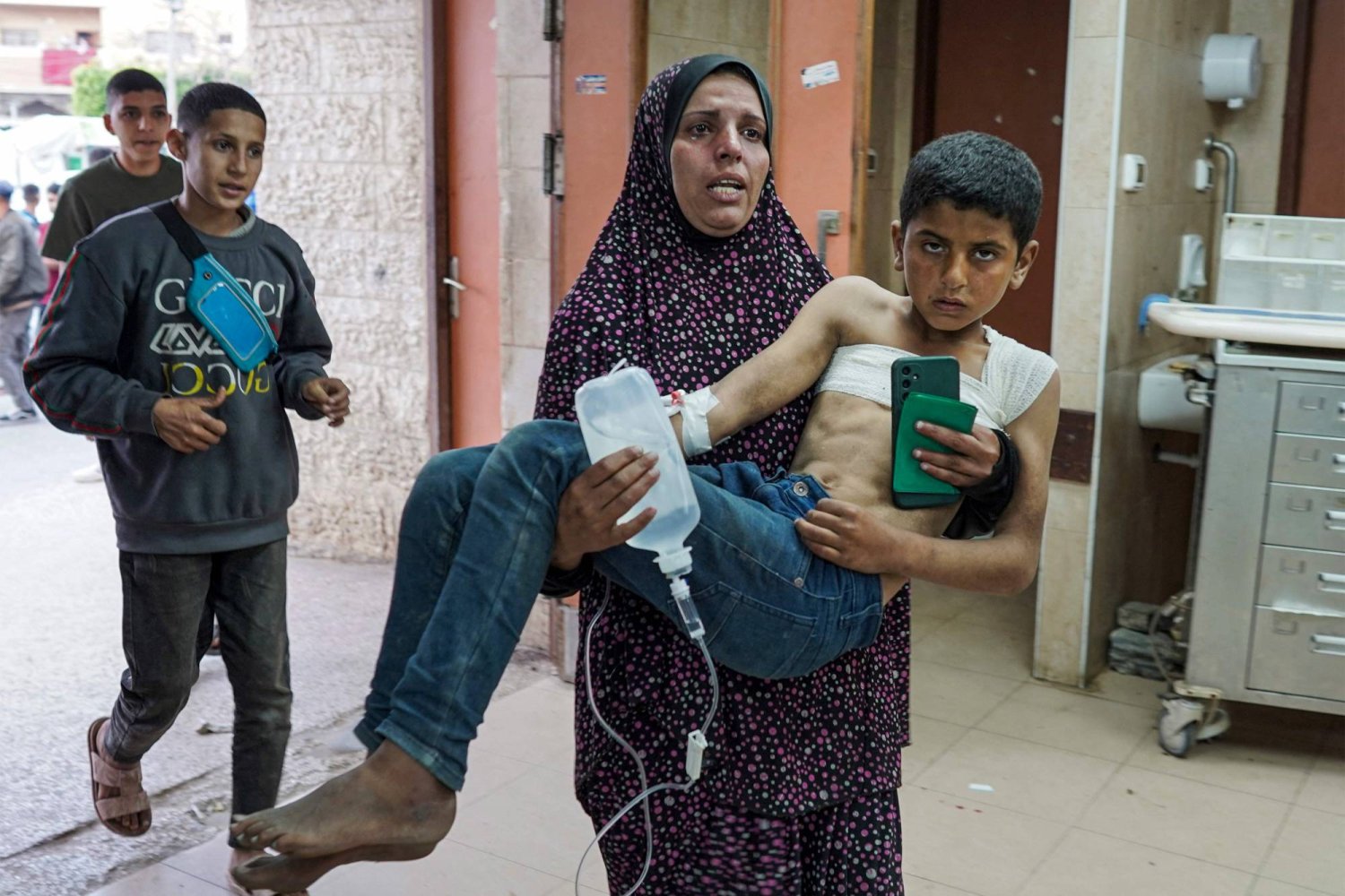 امرأة تحمل طفلاً مصاباً في مستشفى «الأقصى» وسط قطاع غزة (أ.ف.ب)