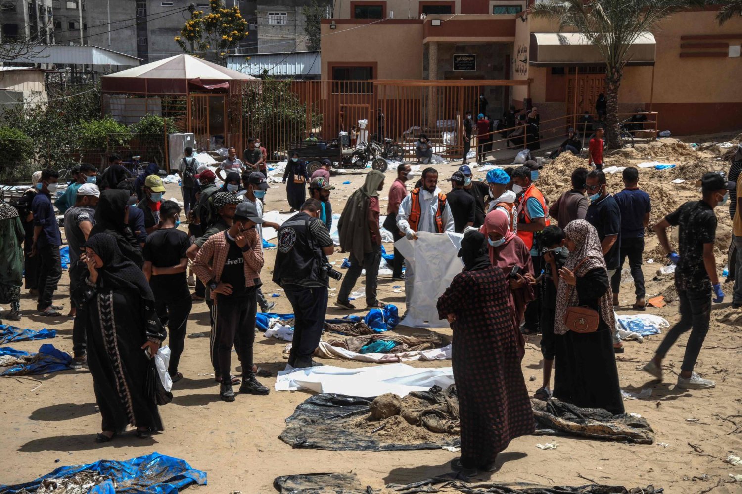 أشخاص وعمال صحيون ينتشلون جثامين عثر عليها في مستشفى ناصر بخان يونس جنوب قطاع غزة (أ.ف.ب)