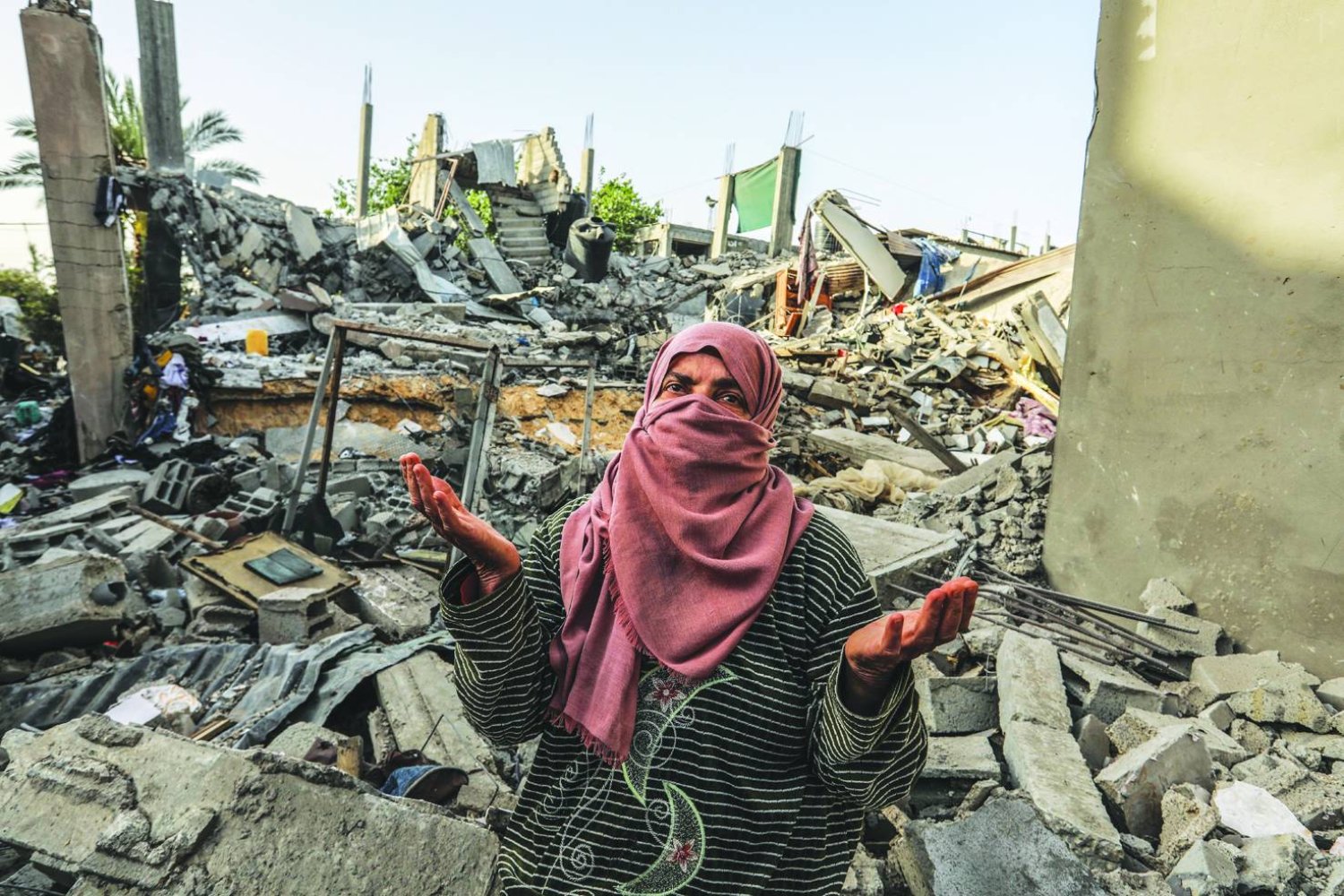 
امرأة فلسطينية تعاين منزلاً دمّرته غارة إسرائيلية في مدينة رفح بجنوب قطاع غزة أمس (د.ب.أ)
