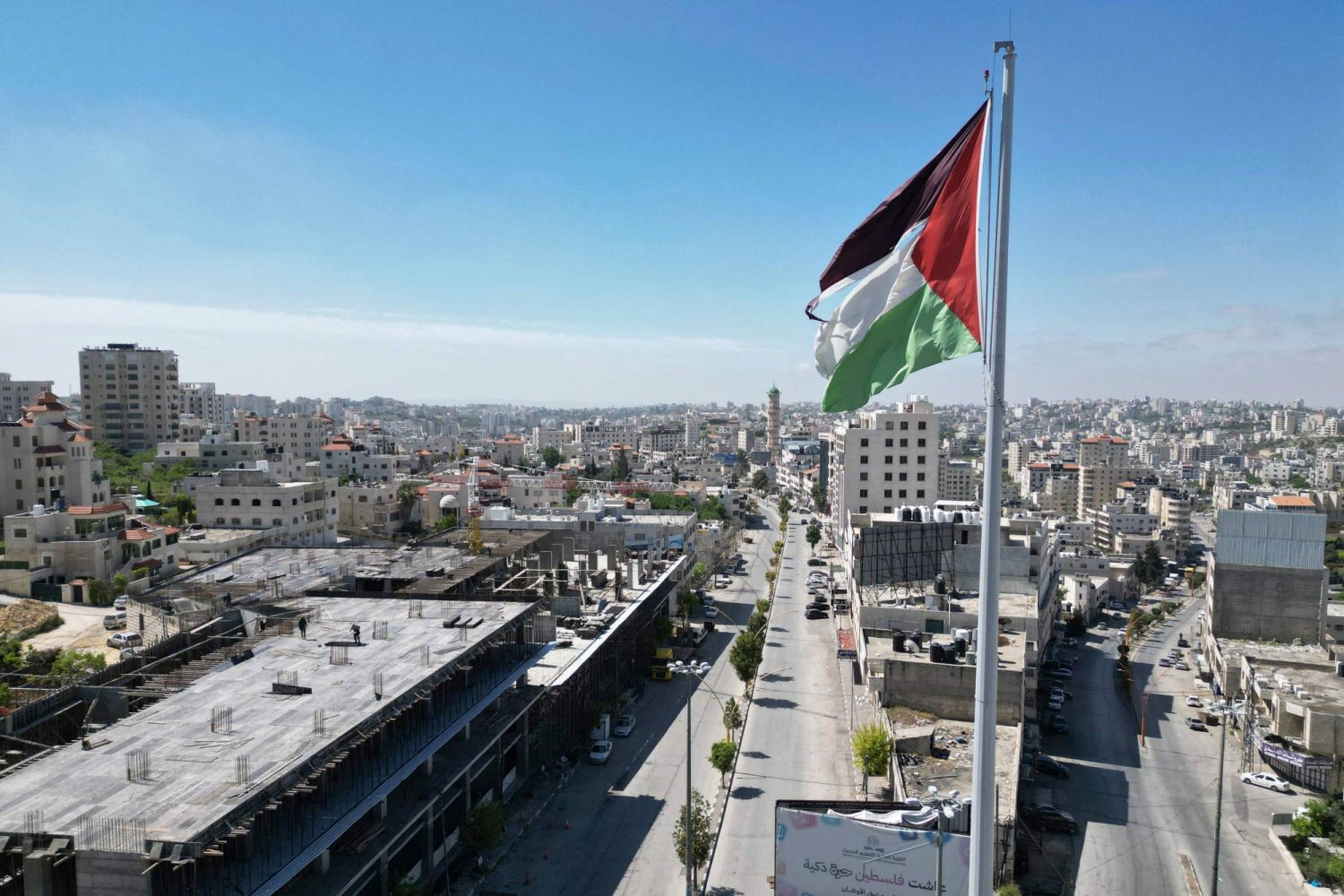 علم فلسطين وخلفه شوارع خالية في مدينة الخليل بالضفة الغربية المحتلة (أ.ف.ب)