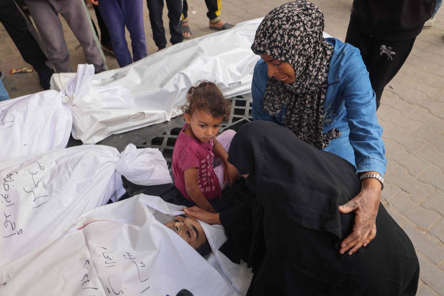 فلسطينيون يبكون بالقرب من جثث أقاربهم الذين قتلوا في القصف الإسرائيلي بمستشفى النجار في رفح بجنوب قطاع غزة (أ.ف.ب)
