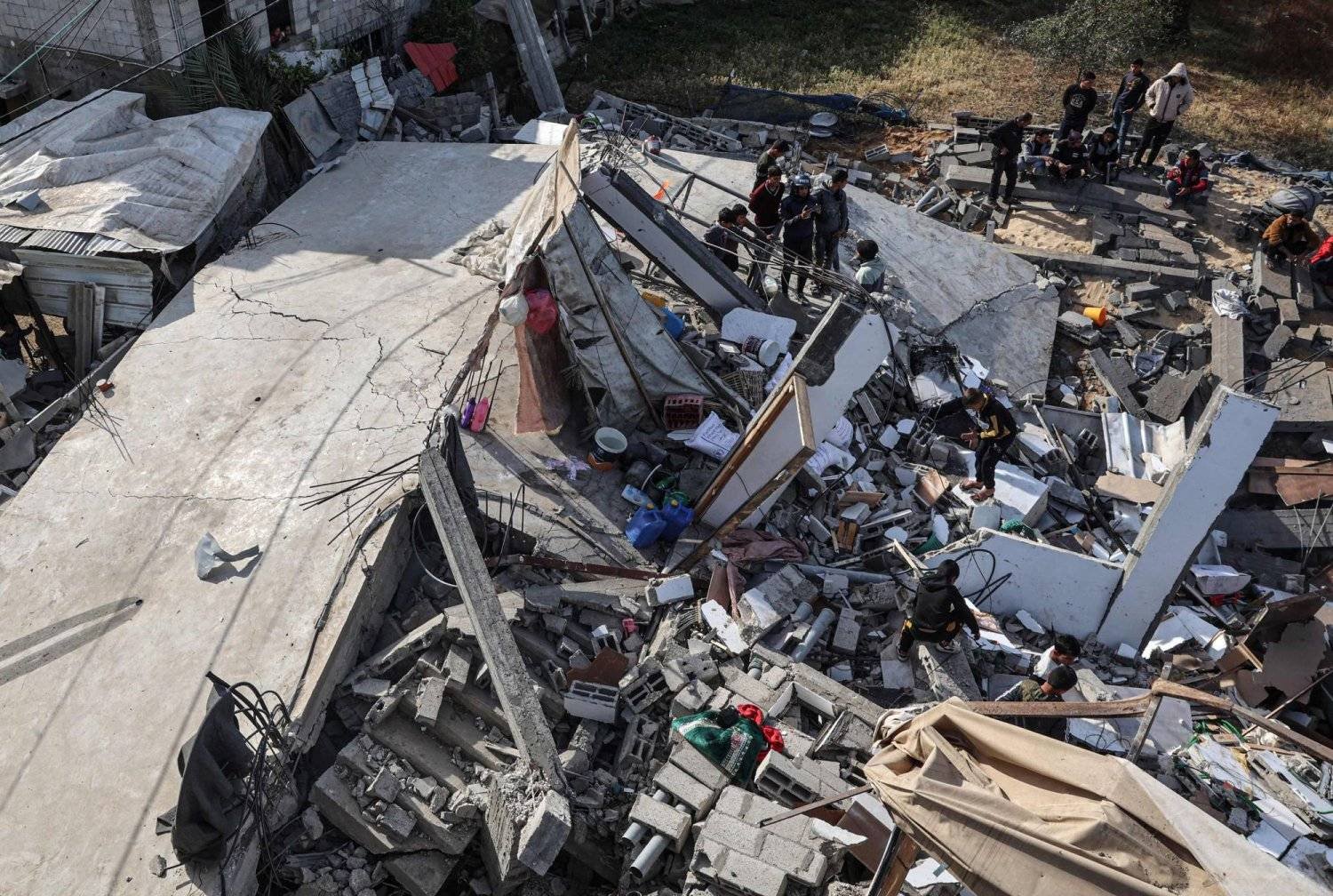 فلسطينيون يقفون على أنقاض منزل أصيب بقصف إسرائيلي في الجزء الشمالي من رفح جنوب غزة (أ.ف.ب)