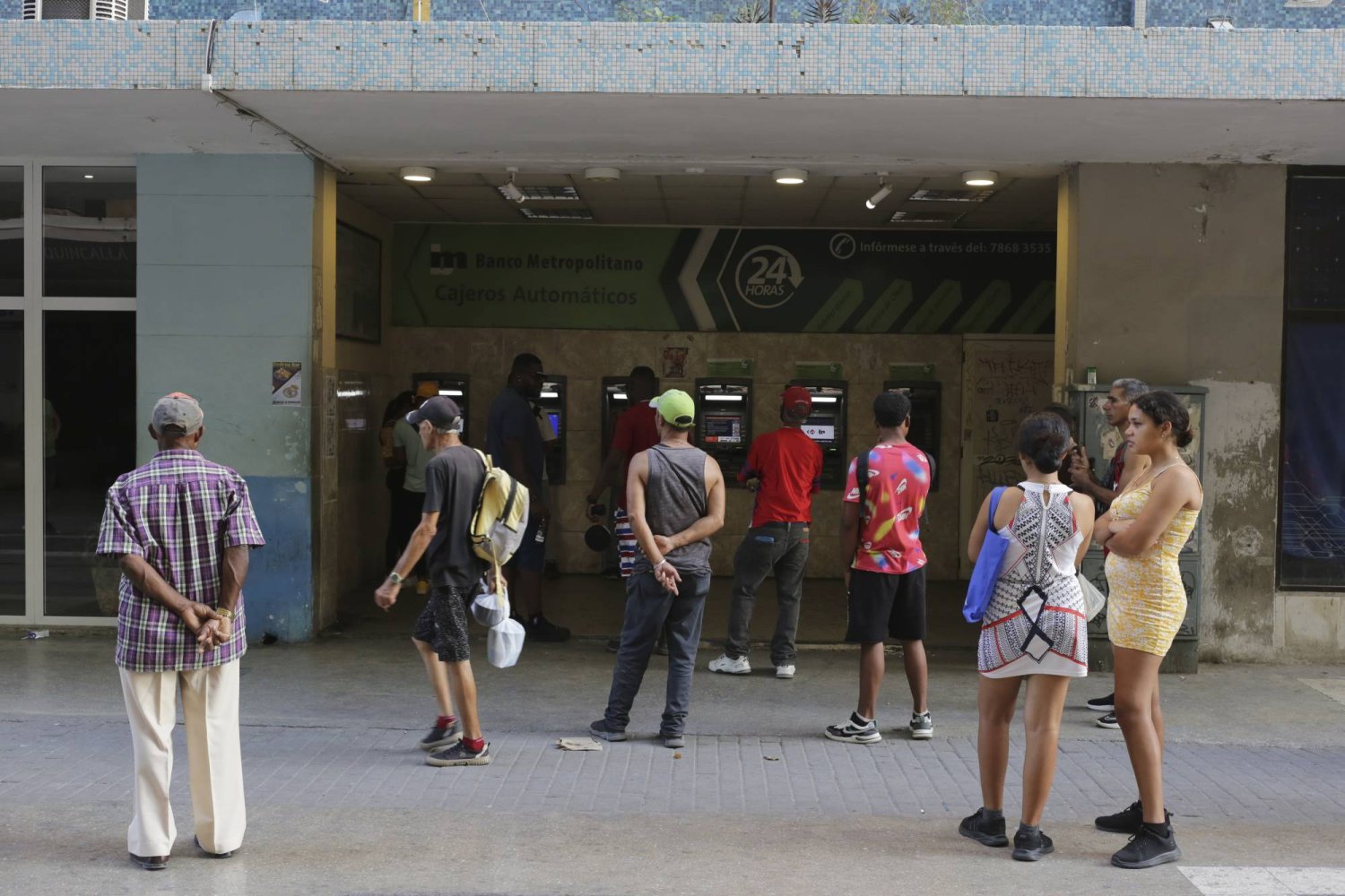 كوبيون ينتظرون أمام آلات صرف النقد الخاصة بأحد المصارف آملين الحصول على بعض المال وسط أزمة نقص في السيولة (أ.ب)