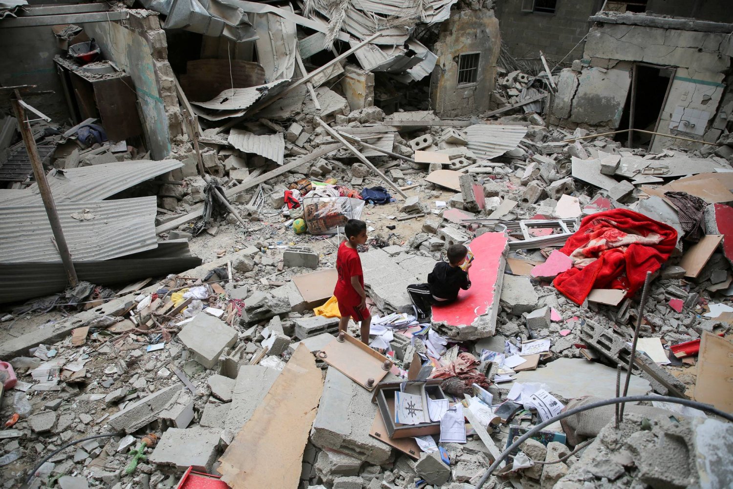 طفلان فلسطينيان فوق ركام مبنى دمره القصف الإسرائيلي في رفح (رويترز)