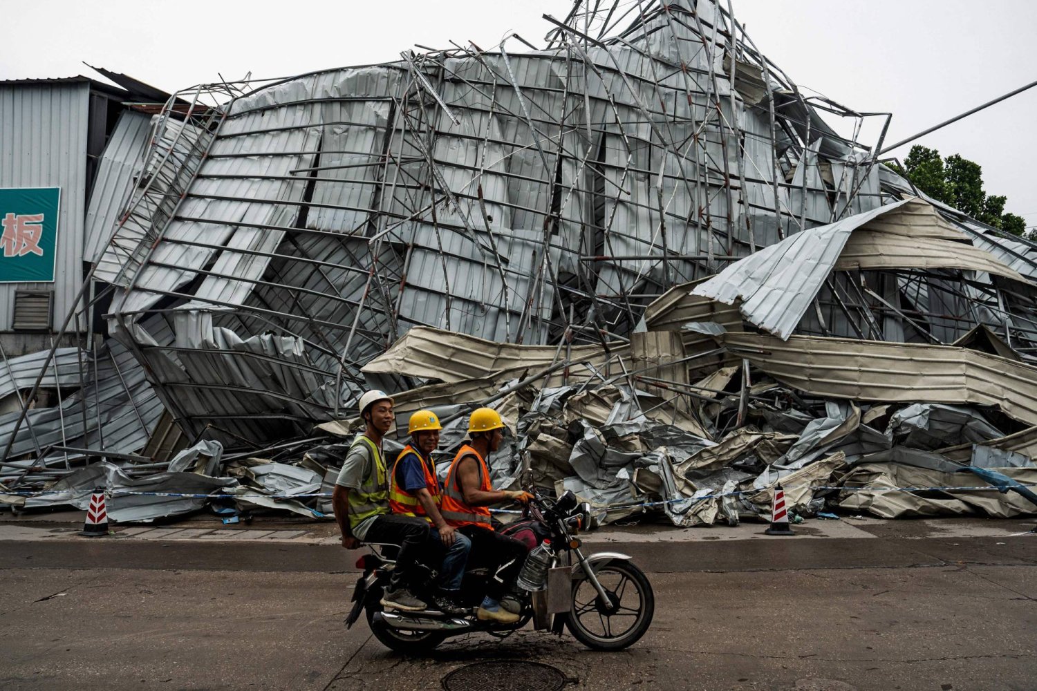 أشخاص يمرون من أمام مبنى متضرر بعد أن ضرب إعصار غوانجو في مقاطعة جوانجدونج بجنوب الصين (أ.ف.ب)
