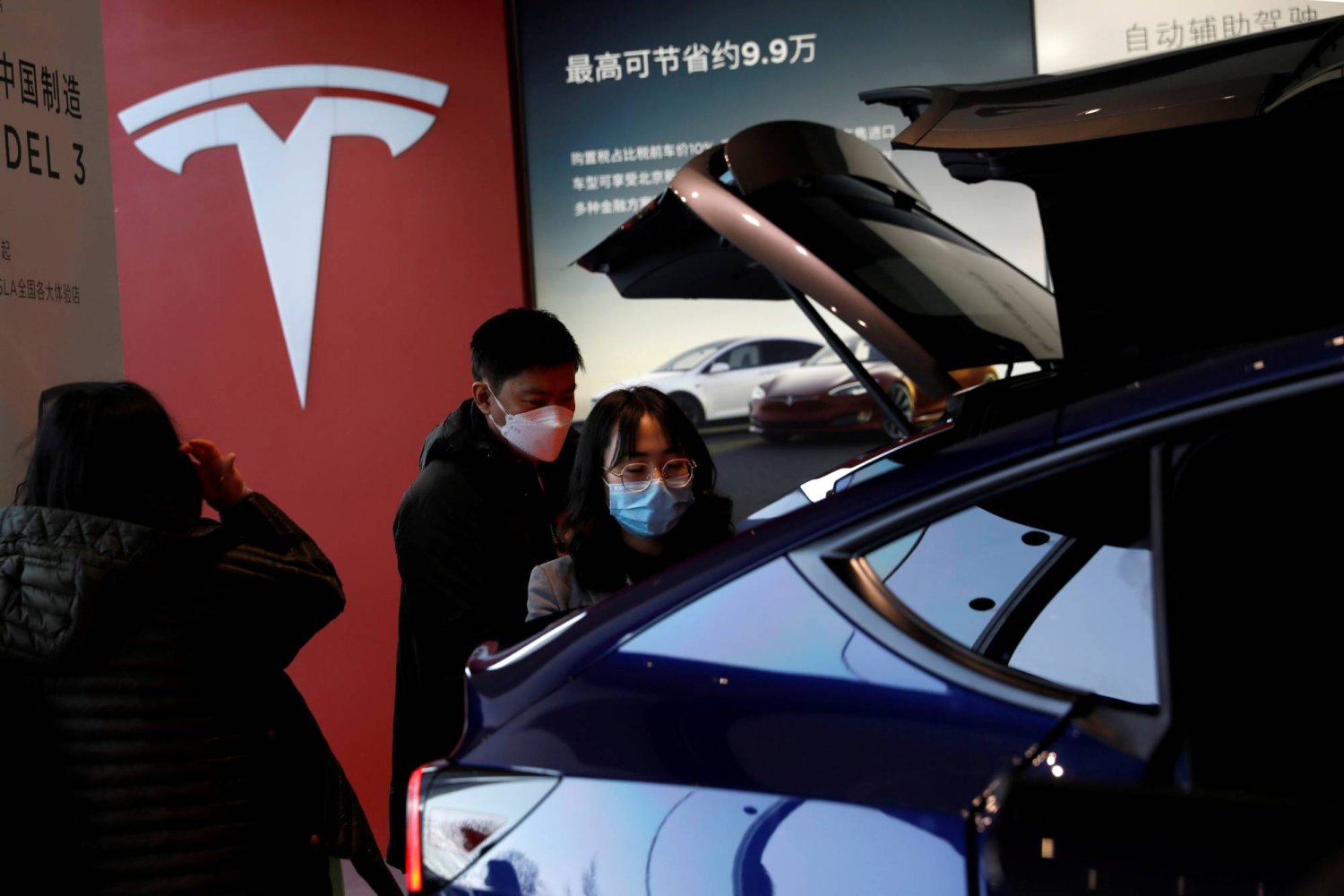 زوار يتفقدون سيارة «تسلا موديل واي» الرياضية متعددة الاستخدامات صينية الصنع في صالة عرض صانع السيارات الكهربائية في بكين (رويترز)