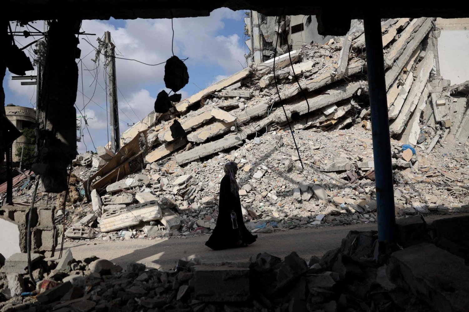 امرأة فلسطينية تسير بجوار أنقاض المباني التي دمرت في القصف الإسرائيلي السابق في رفح جنوب قطاع غزة (أ.ف.ب)