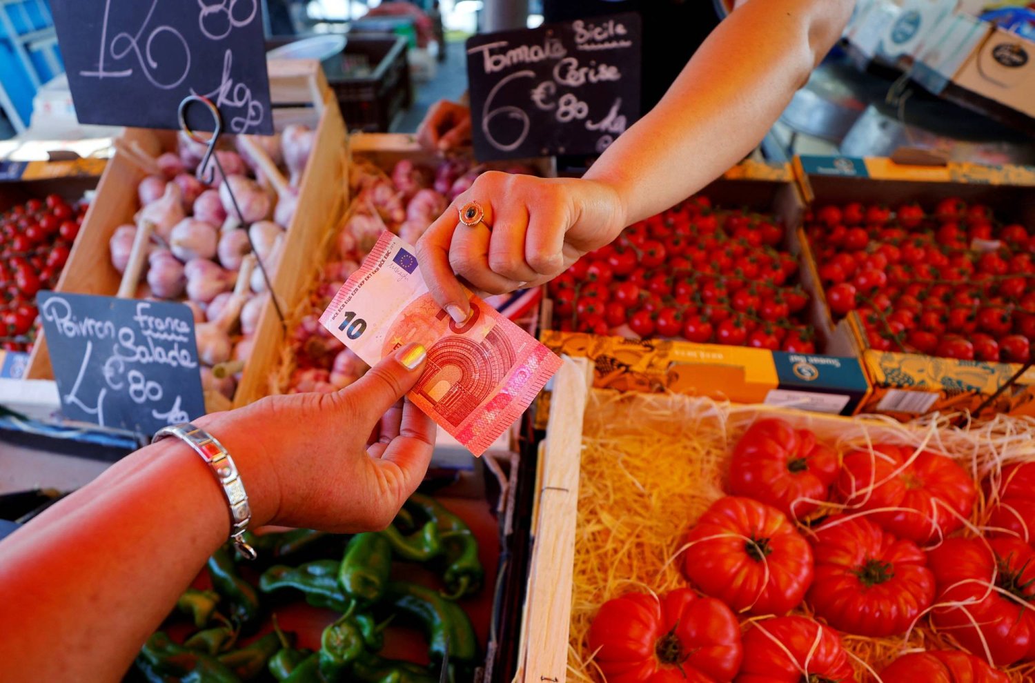 متسوق يدفع بورقة نقدية بقيمة 10 يوروات في سوق محلية في نيس بفرنسا (رويترز) 