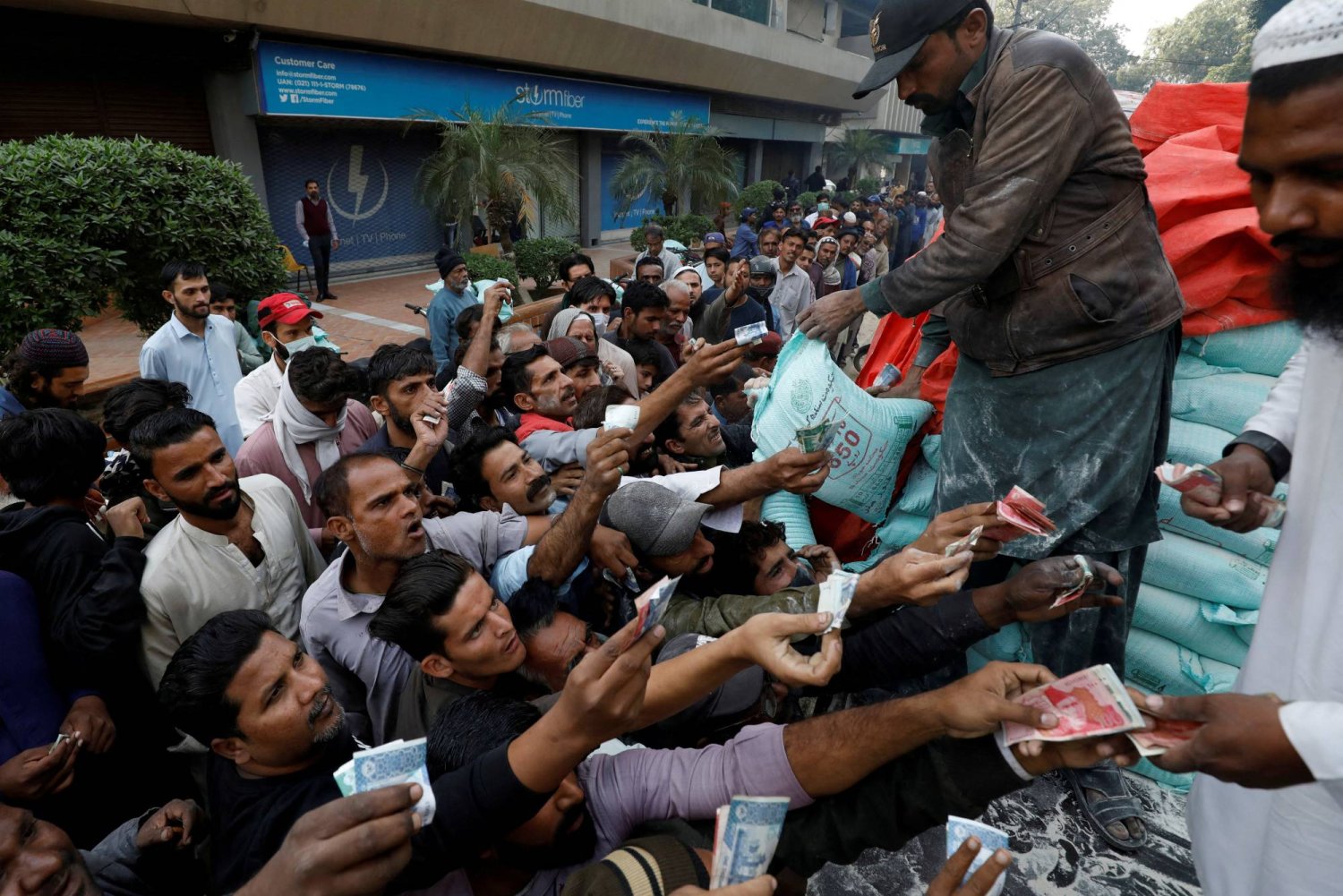 رجال يحاولون شراء أكياس الدقيق المدعم من شاحنة في كراتشي باكستان (رويترز)