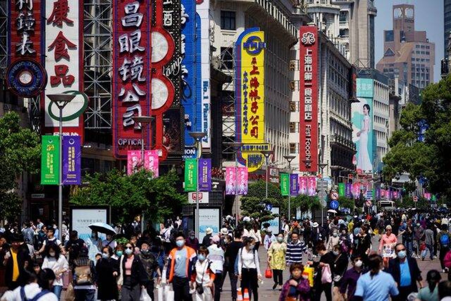 أشخاص يسيرون على طول طريق نانجينغ للمشاة وهي منطقة التسوق الرئيسية في شنغهاي بالصين (رويترز)