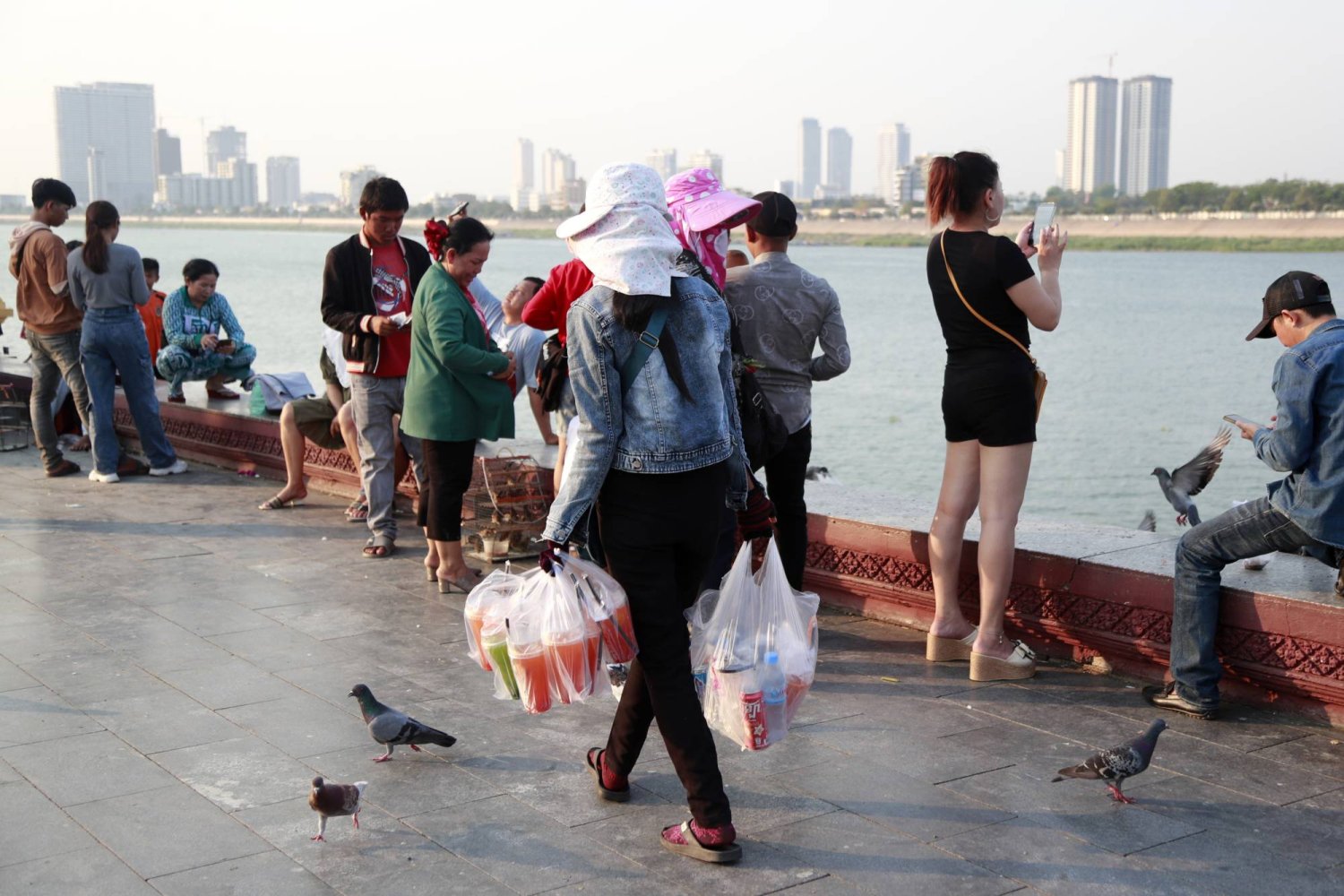 امرأة تحمل مشروبات غازية باردة للبيع خارج القصر الملكي في بنوم بنه بكمبوديا 29 أبريل 2024 (إ.ب.أ)