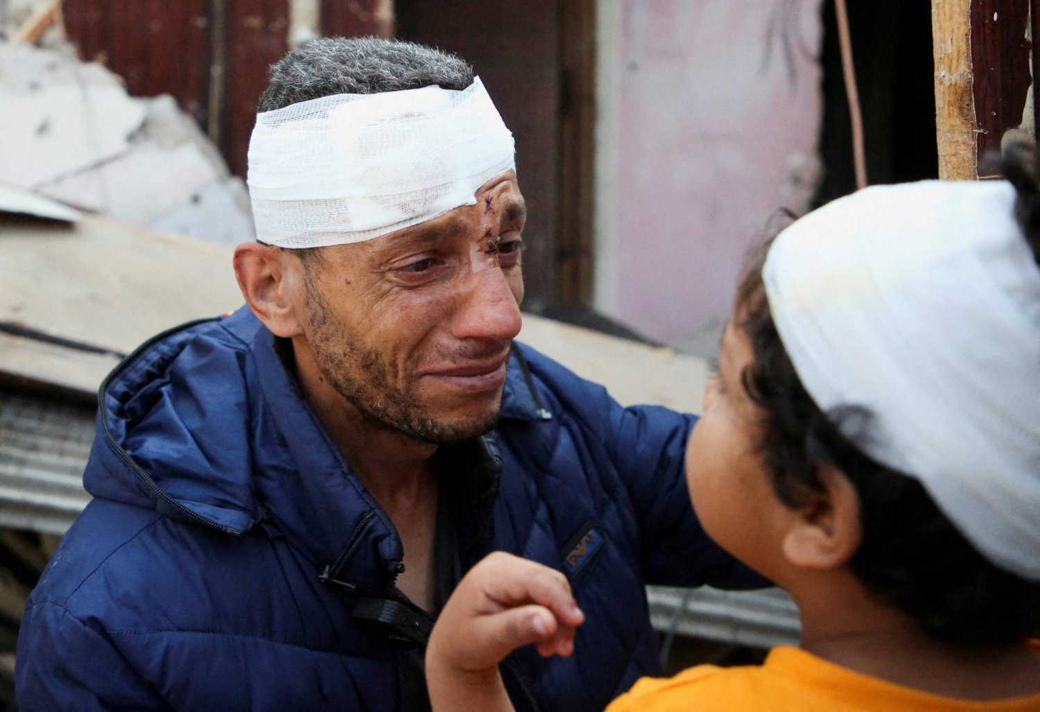 رجل فلسطيني جريح وابنه المصاب في موقع غارة إسرائيلية على منزل وسط برفح بجنوب قطاع غزة (رويترز)
