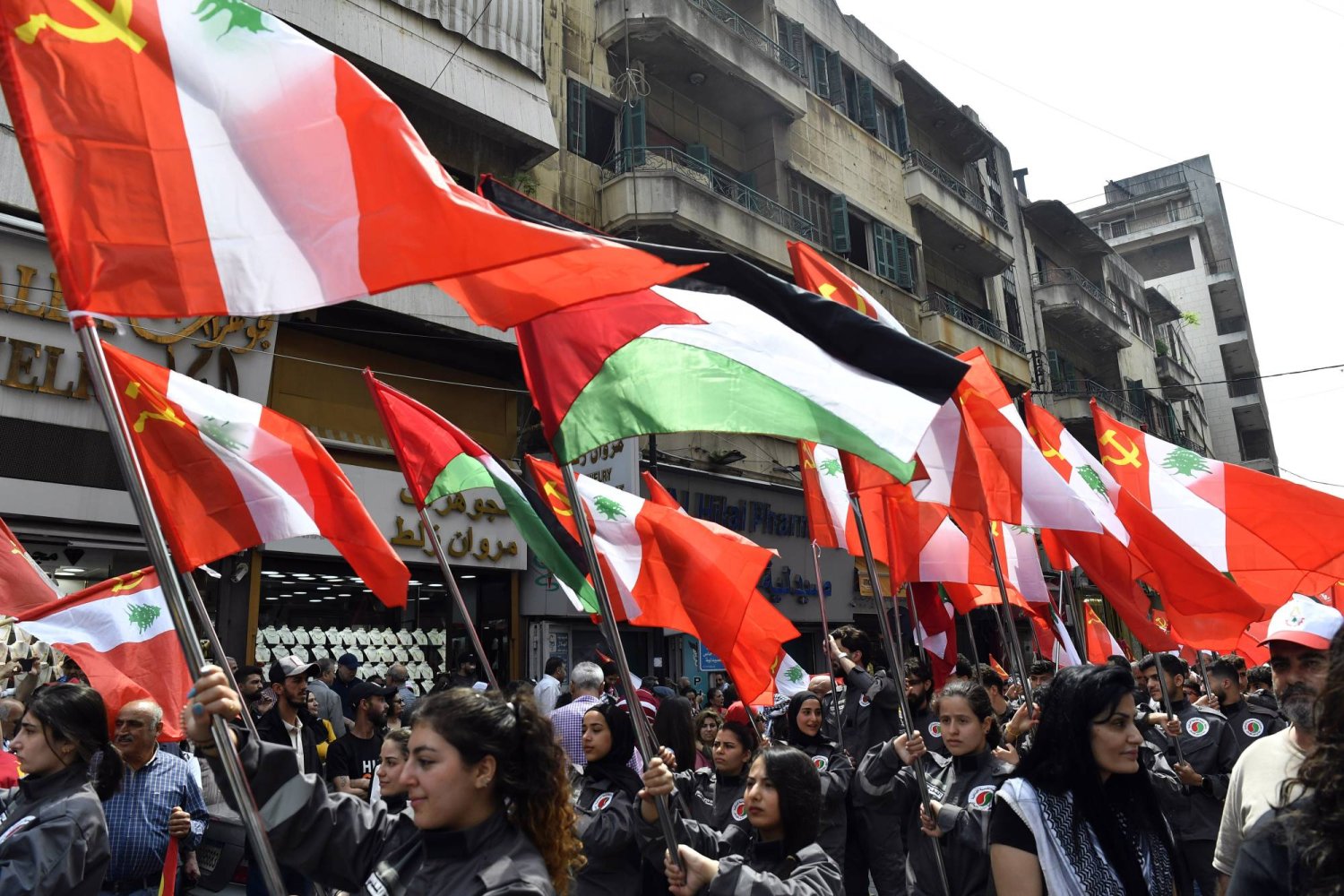 أحزاب ومواطنون لبنانيون يرفعون أعلاماً فلسطينية ولبنانية خلال مشاركتهم في مظاهرة بمناسبة عيد العمال في بيروت (إ.ب.أ)