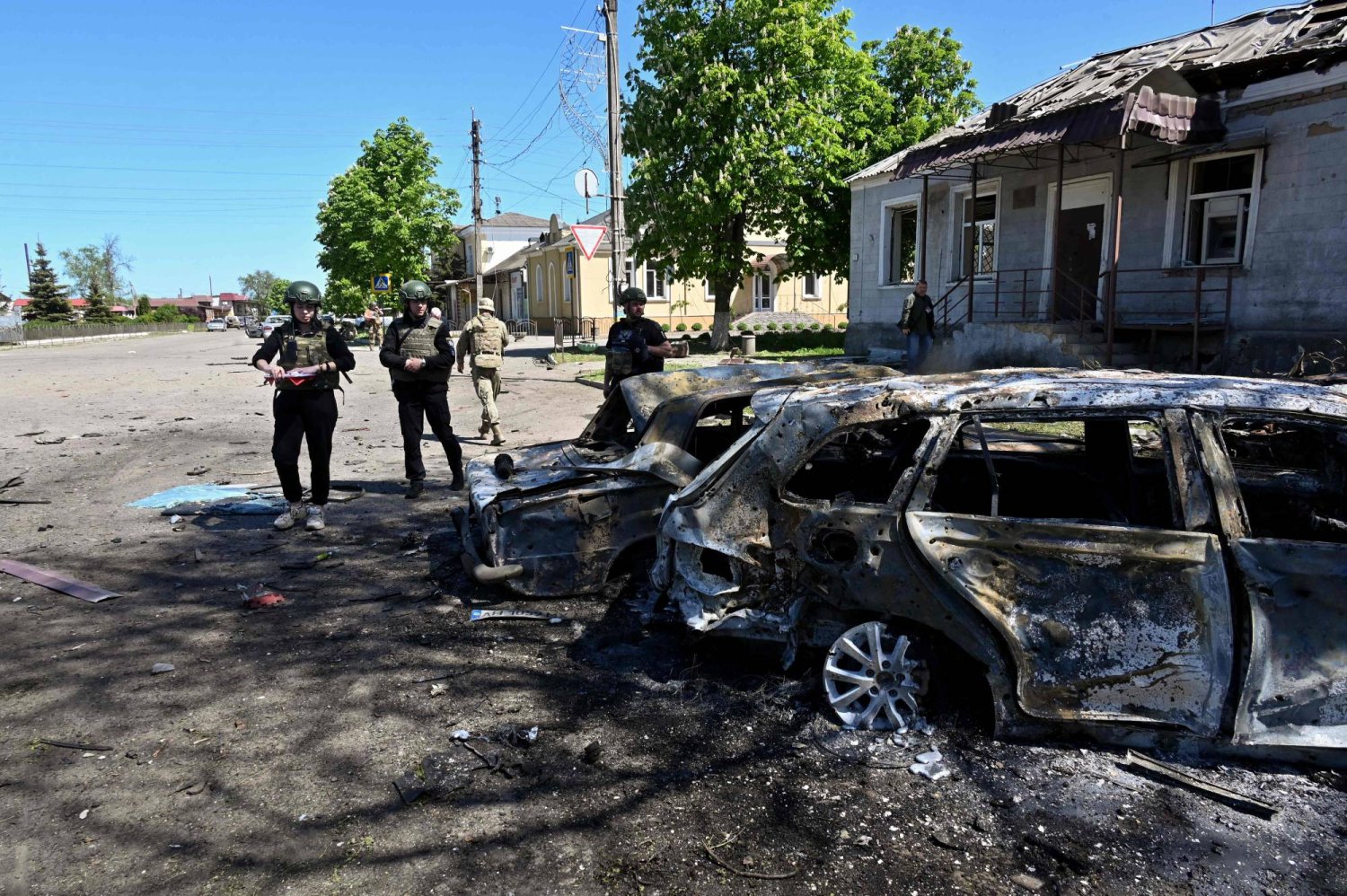 عناصر من الشرطة الأوكرانية يتفقدون سيارات مدمرة في موقع ضربة صاروخية روسية على قرية زولوتشيف بمنطقة خاركيف في 1 مايو 2024 (أ.ف.ب)