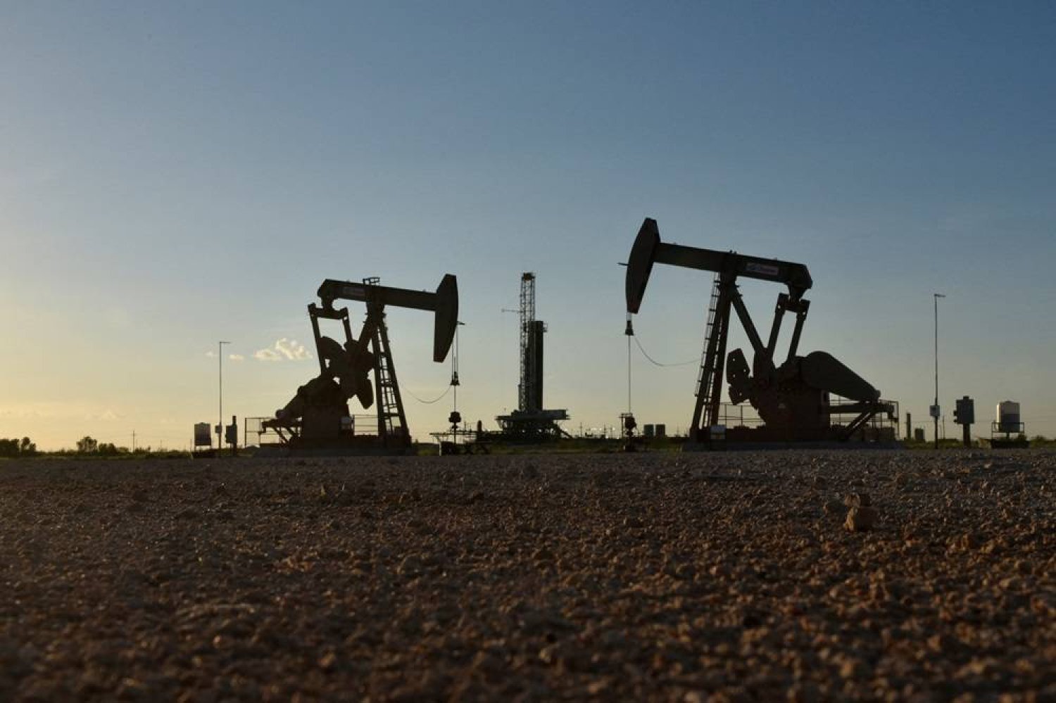 Pump jacks operate in front of a drilling rig in an oil field in Midland, Texas US August 22, 2018. (Reuters)