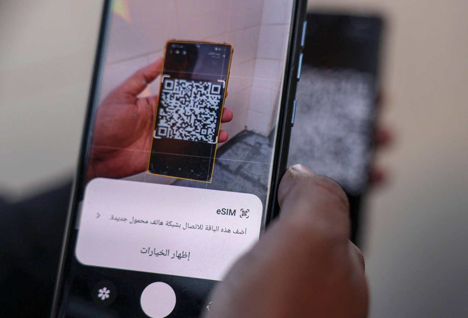 صحافي فلسطيني يحاول ربط هاتفه بشريحة إلكترونية لتفادي انقطاع الاتصالات في غزة (أ.ف.ب)