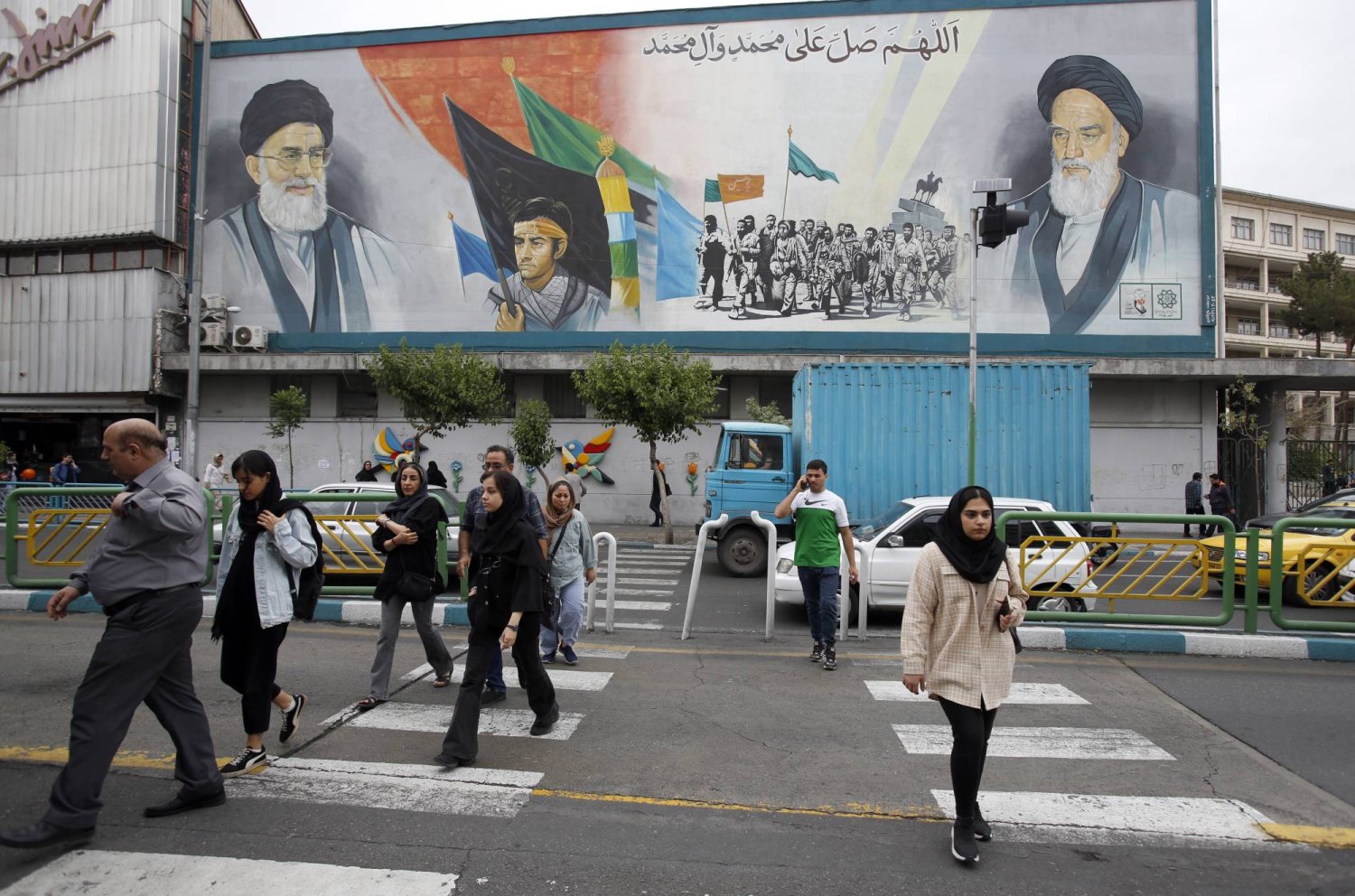 إيرانيون في أحد شوارع طهران وتظهر جدارية كبيرة عن «الثورة الإسلامية» (إ.ب.أ)