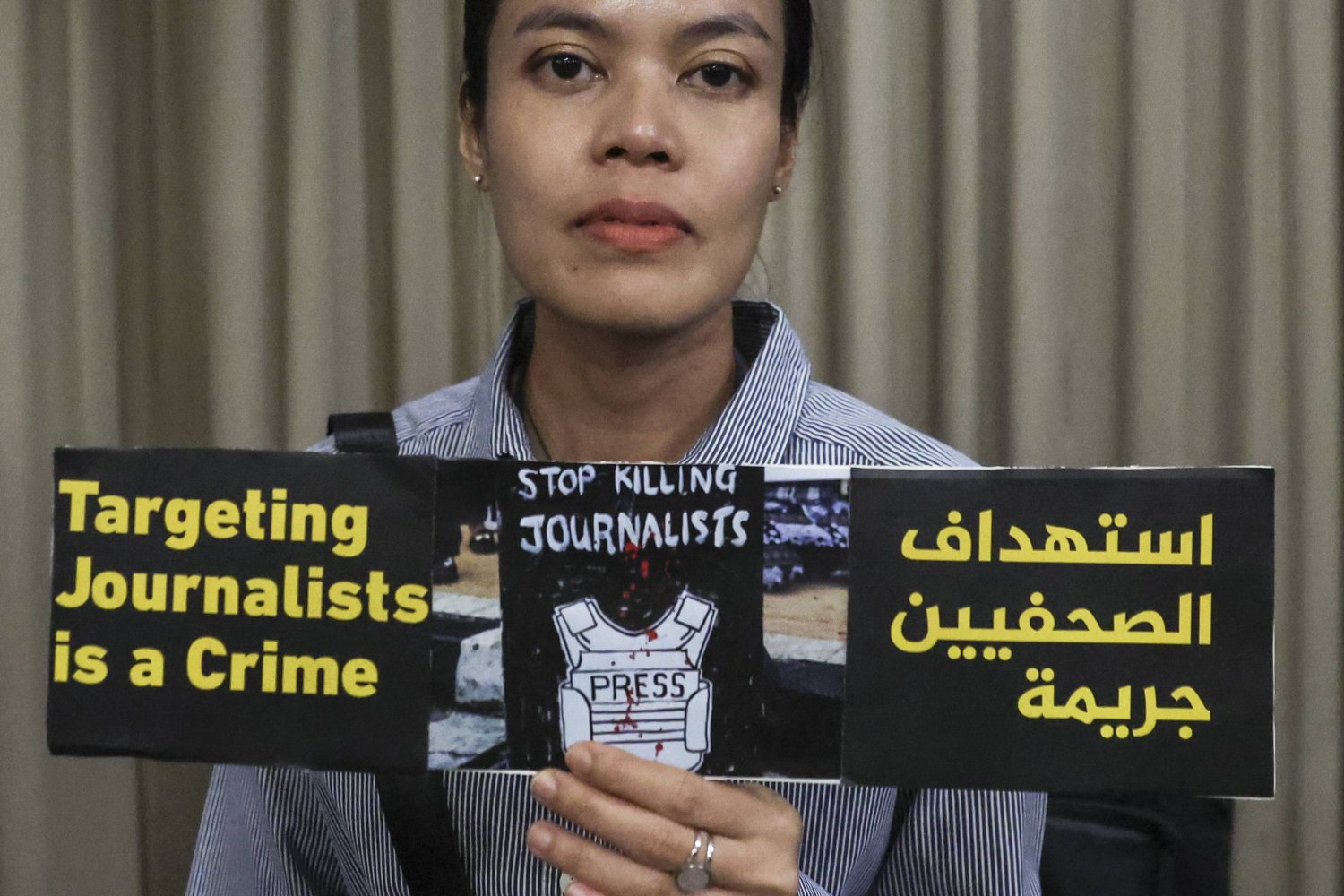 صحفية ترفع لافتةً تدين قتل الصحافيين خلال مسيرة تضامنية في ماليزيا مع الإعلاميين الذين قتلوا خلال تغطية أحداث غزة (إ.ب.أ)