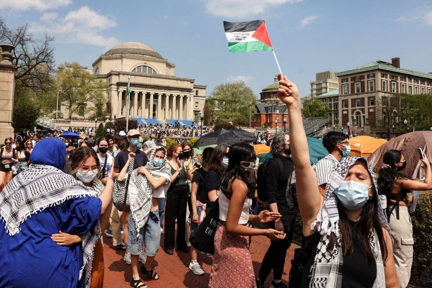 كوفيات وأعلام فلسطينية يرفعها الطلاب المحتجون في قلب حرم جامعة كولمبيا بنيويورك (غيتي)