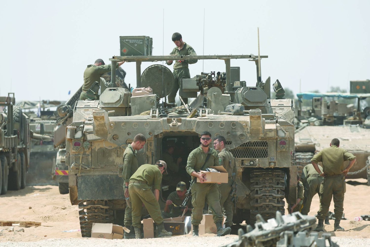جنود إسرائيليون يفحصون المعدات العسكرية في موقع على الحدود الجنوبية مع قطاع غزة قرب رفح (إ.ب.أ)
