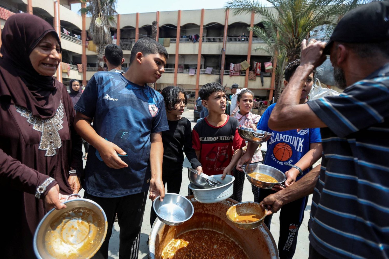 فلسطينيون ينتظرون تلقي طعام توزعه منظمة «المطبخ المركزي العالمي» في دير البلح بوسط قطاع غزة (رويترز)