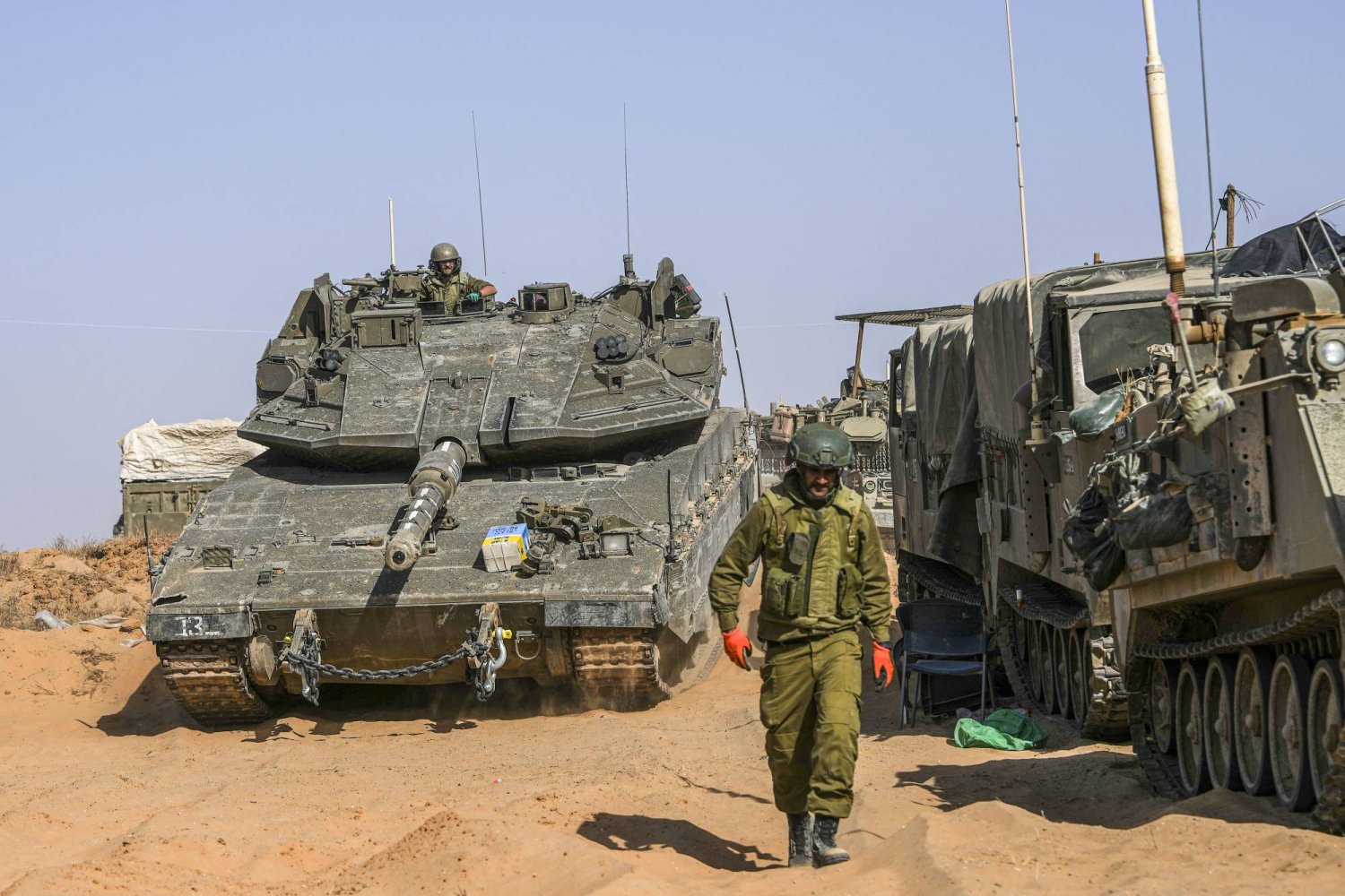 جندي إسرائيلي متقدماً دبابتين في منطقة على مشارف قطاع غزة (أ.ب)