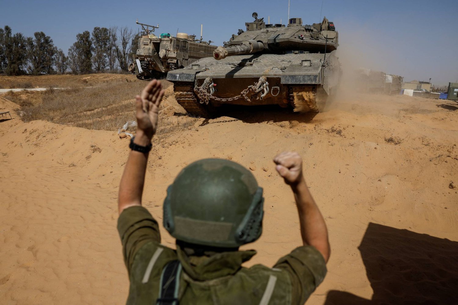جندي إسرائيلي يوجه دبابة بالقرب من حدود غزة (رويترز)