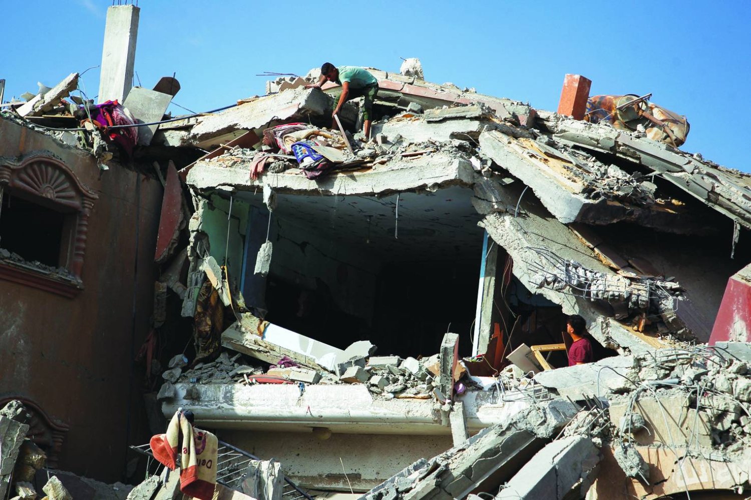 
فلسطينيون يتفقدون موقع غارة إسرائيلية على منزل في رفح جنوب قطاع غزة الأحد (رويترز)
