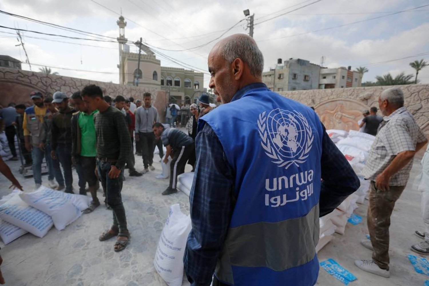 أحد موظفي «الأونروا» خلال توزيع أجولة الطحين على النازحين في غزة (حساب «الأونروا» على «إكس»)