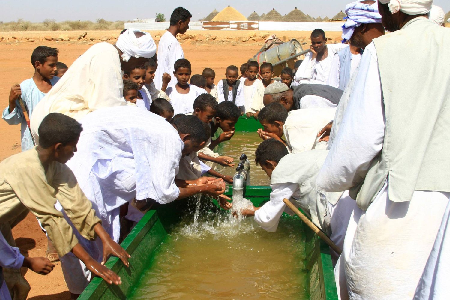 سودانيون يشربون من مياه استخرجت من بئر جوفية في ولاية القضارف شرق السودان (أ.ف.ب)