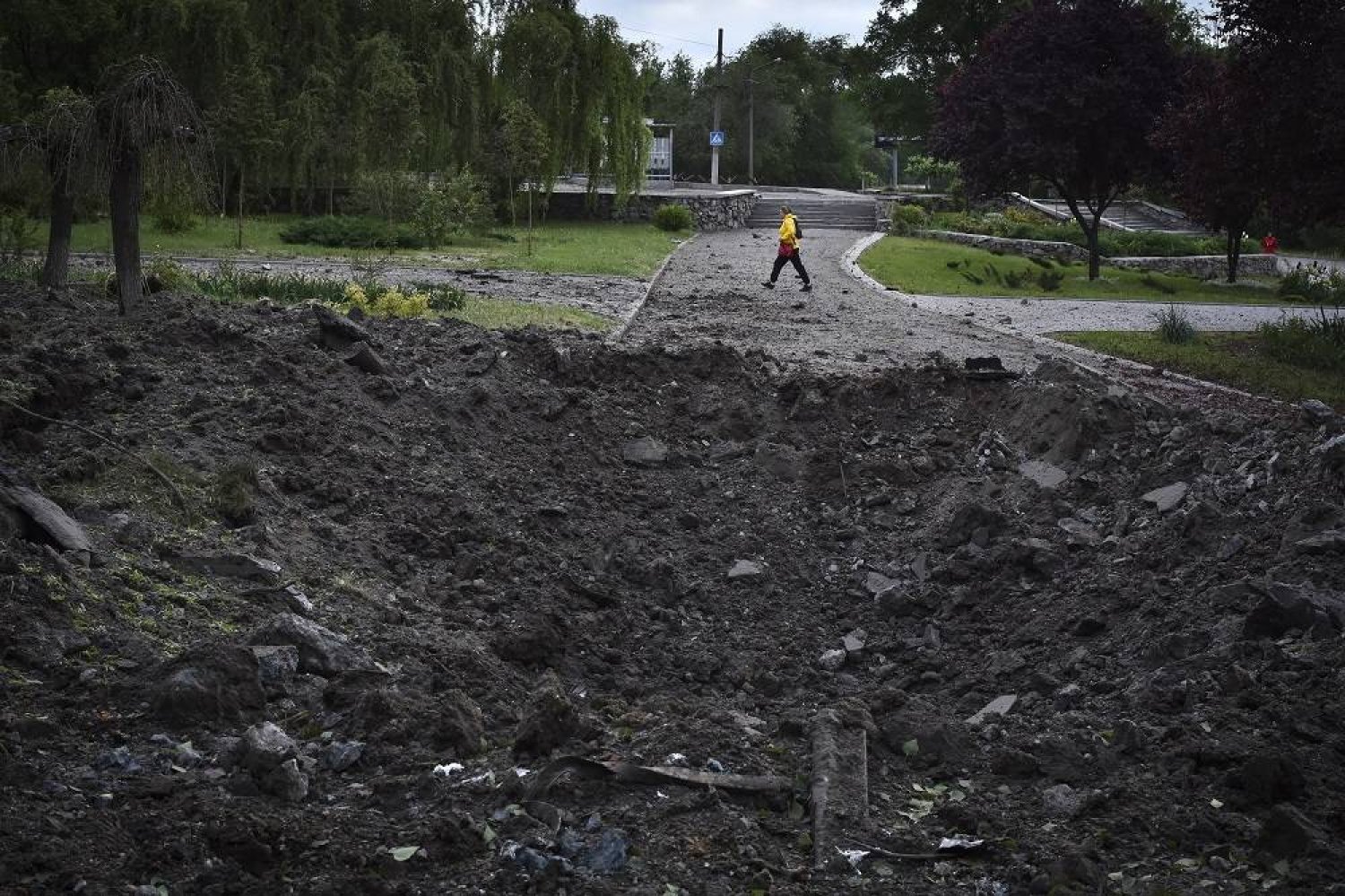 A woman walks in front of a crater caused by a Russian missile attack in Zaporizhzhia, Ukraine, Wednesday, May 8, 2024. (AP)