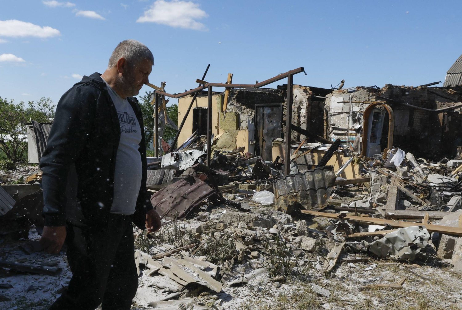 رجل يسير بجانب منزل تعرّض للدمار بعد إطلاق صاروخي ليلي في قرية كراسيليفكا بالقرب من كييف (إ.ب.أ)