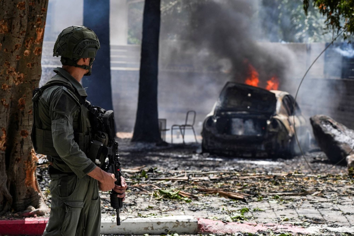 جندي إسرائيلي يقف إلى جانب سيارة محترمة في كريات شمونة إثر قصف «حزب الله» (رويترز)